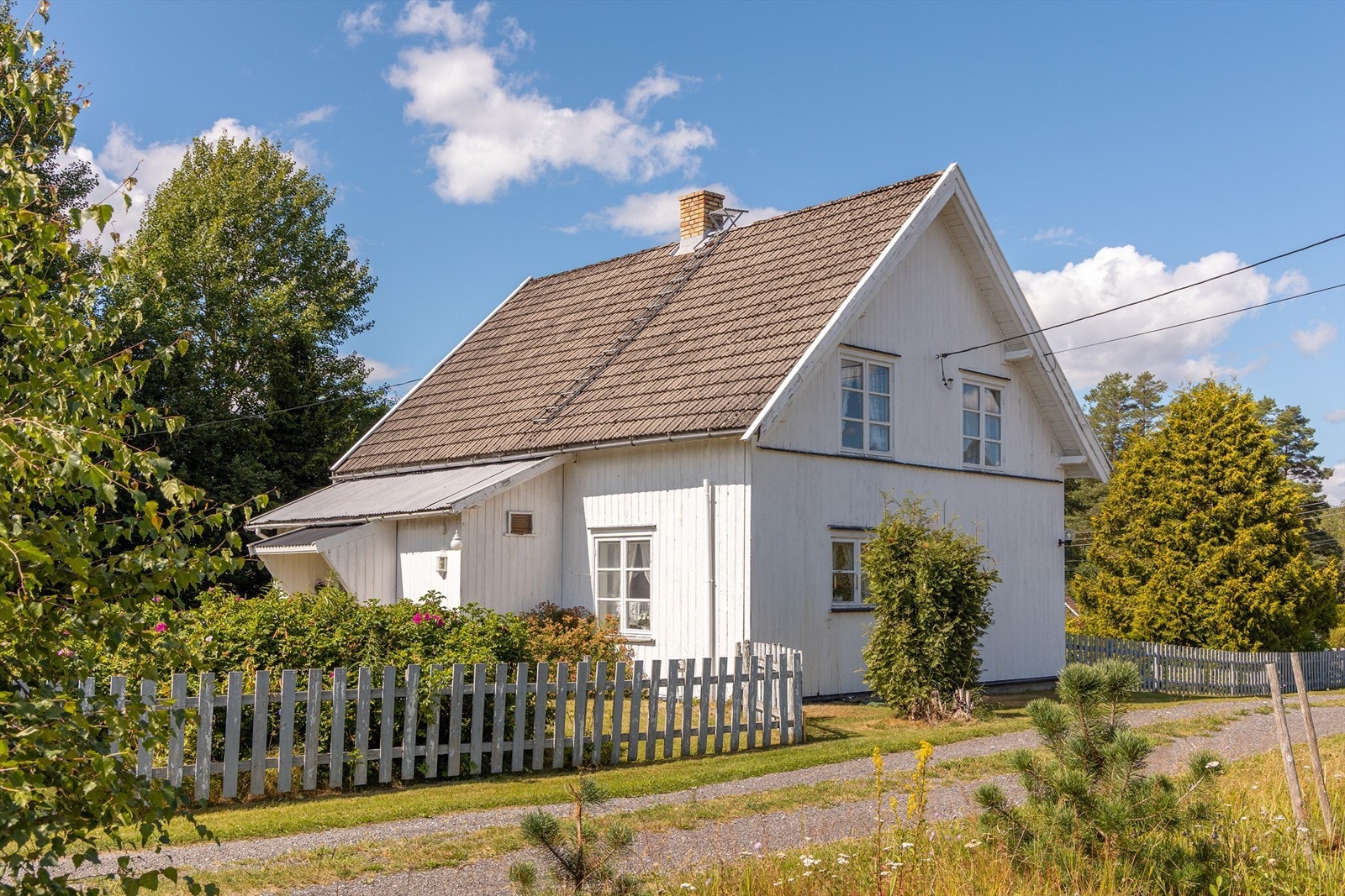 Huset er omgitt av en hage og hvit stakittgjerde som gir en skjermet og privat følelse. Galleribilde