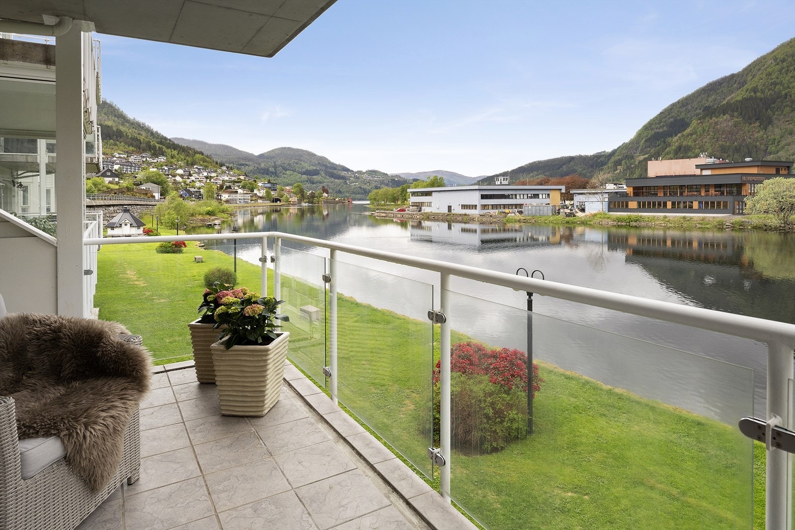 Frå balkongen ser ein ned på sameiget sitt felles grøntareal med stiar langs elva. Galleribilde