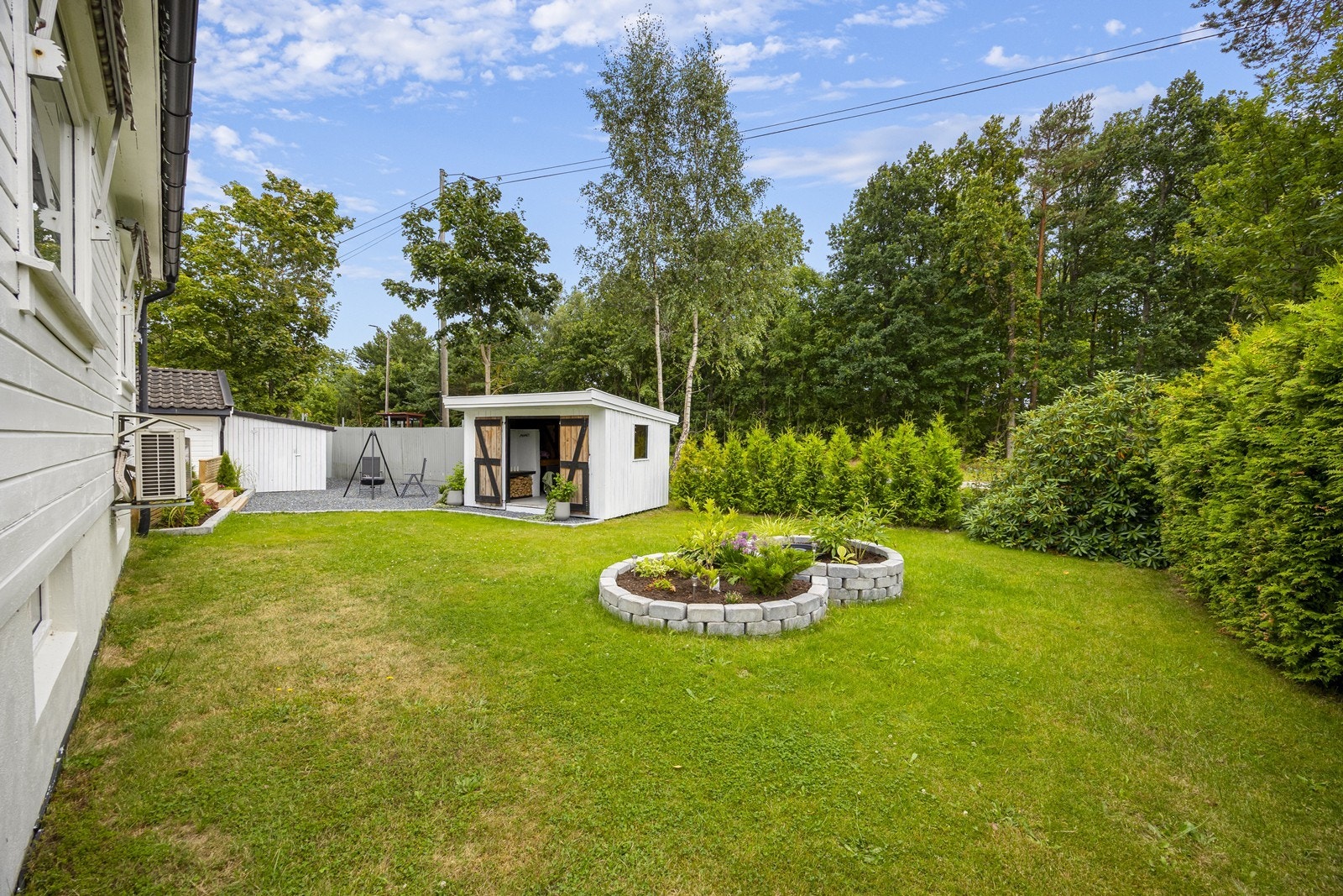 Hagen er romslig og inneholder en pen opparbeidet blomsterbed og plen. Galleribilde