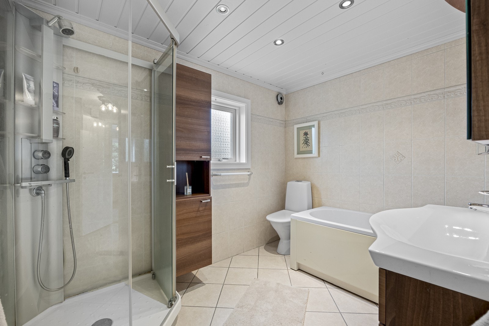 Badet er flislagt og utstyrt med både dusjkabinett og badekar, noe som gir flere muligheter for bruk. Galleribilde