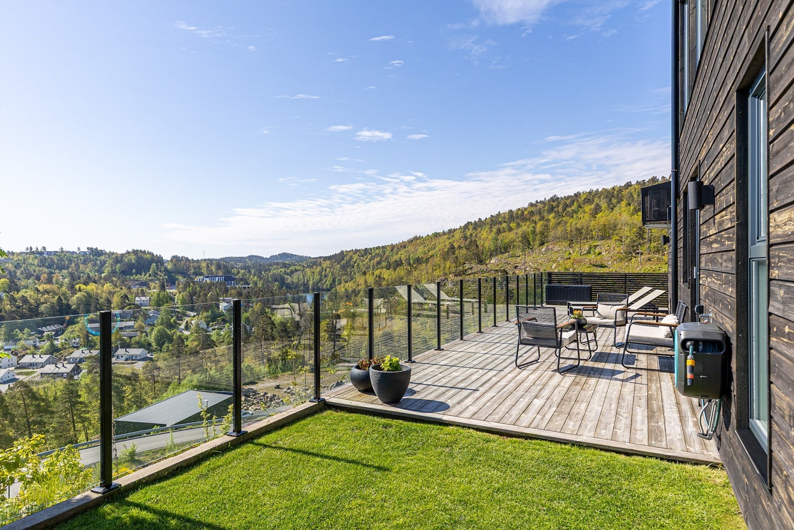 Flott, opparbeidet uteplass med glassrekkverk, terrasse, plen og asfaltert tun. Galleribilde
