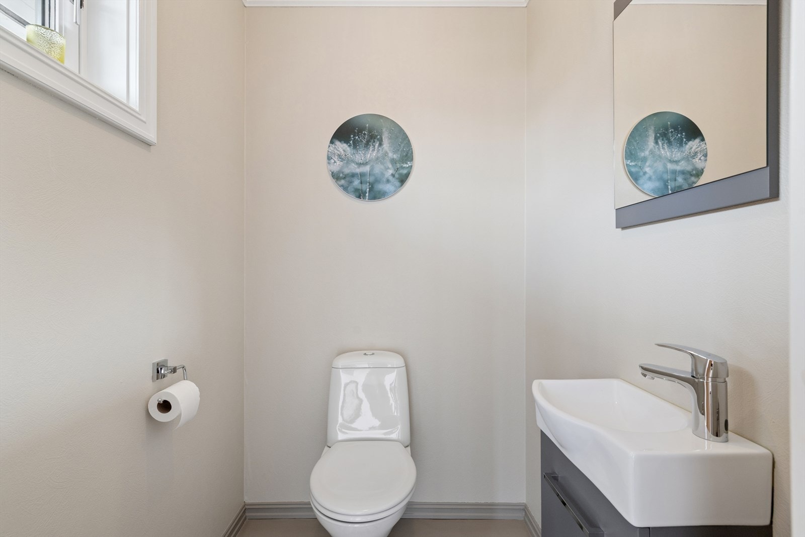 Toalettrommet er holdt i nøytrale fargetoner med beige vegger og vindu som bidrar med naturlig lys. Rommet er utstyrt med servant/håndvask og toalett. Galleribilde