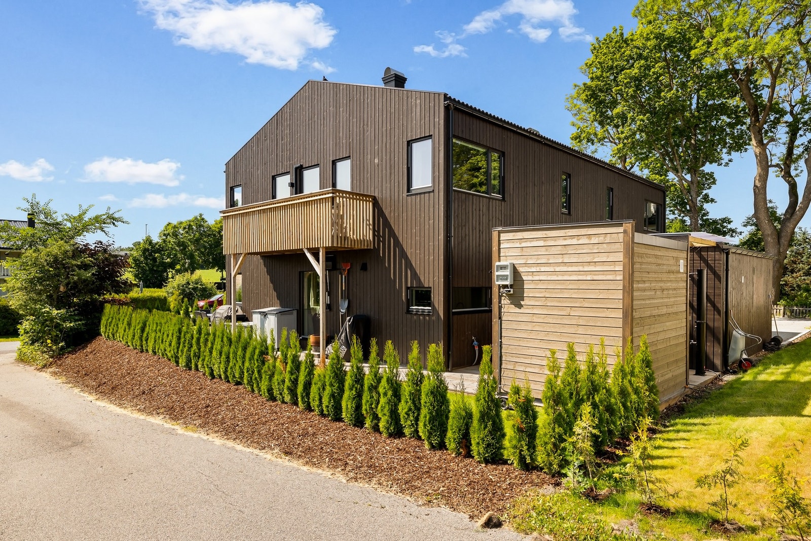 Tilnærmet flat tomt med plen, beplantning og skjermende hekk Galleribilde