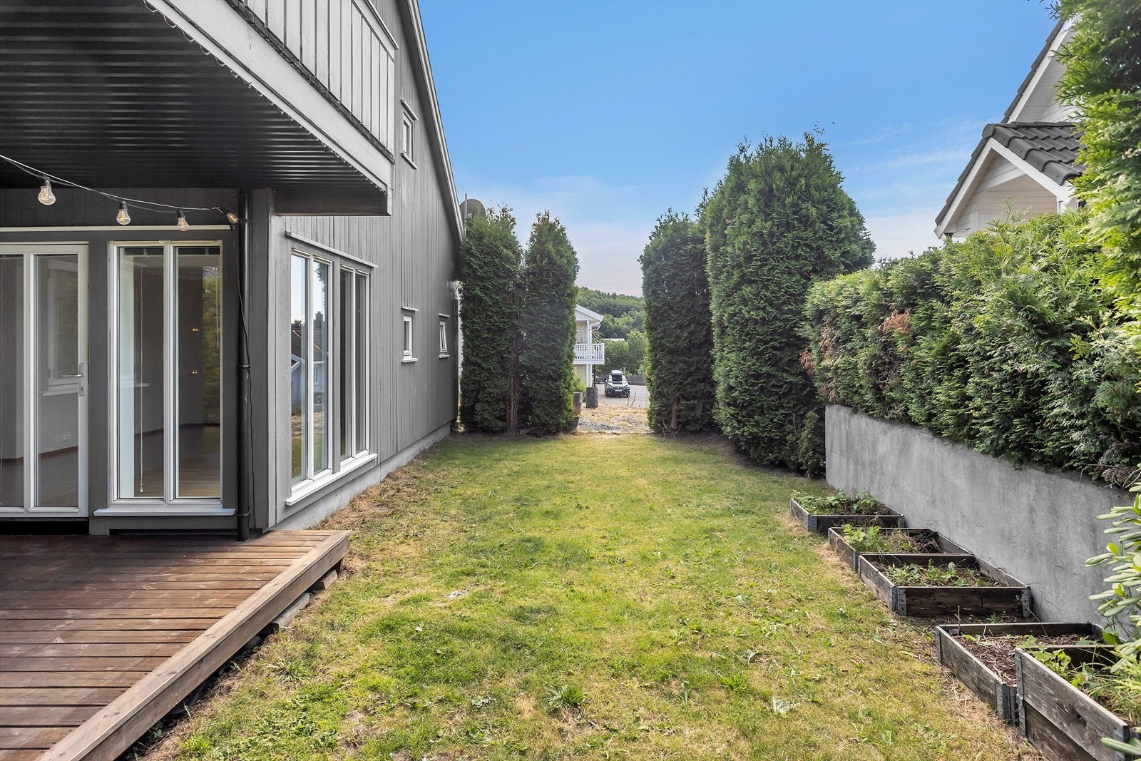 Terrassen gir direkte tilgang til et stort og skjermet hageareal omkranset av hekk, som skaper en privat og innbydende atmosfære. Galleribilde