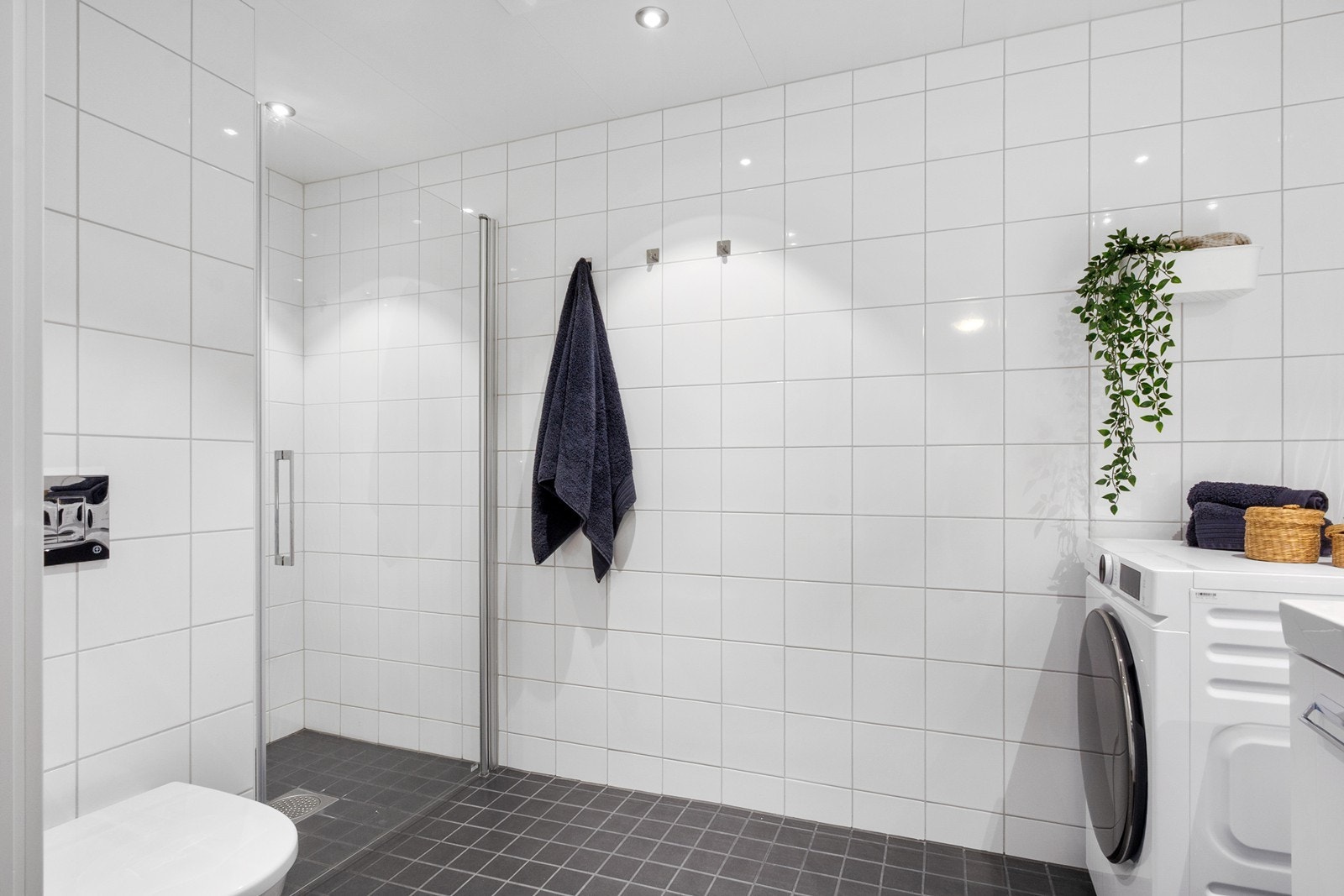 Badet i boligens 1. etasje har dusjhjørne med glassdør og røropplegg for vaskemaskin. Galleribilde