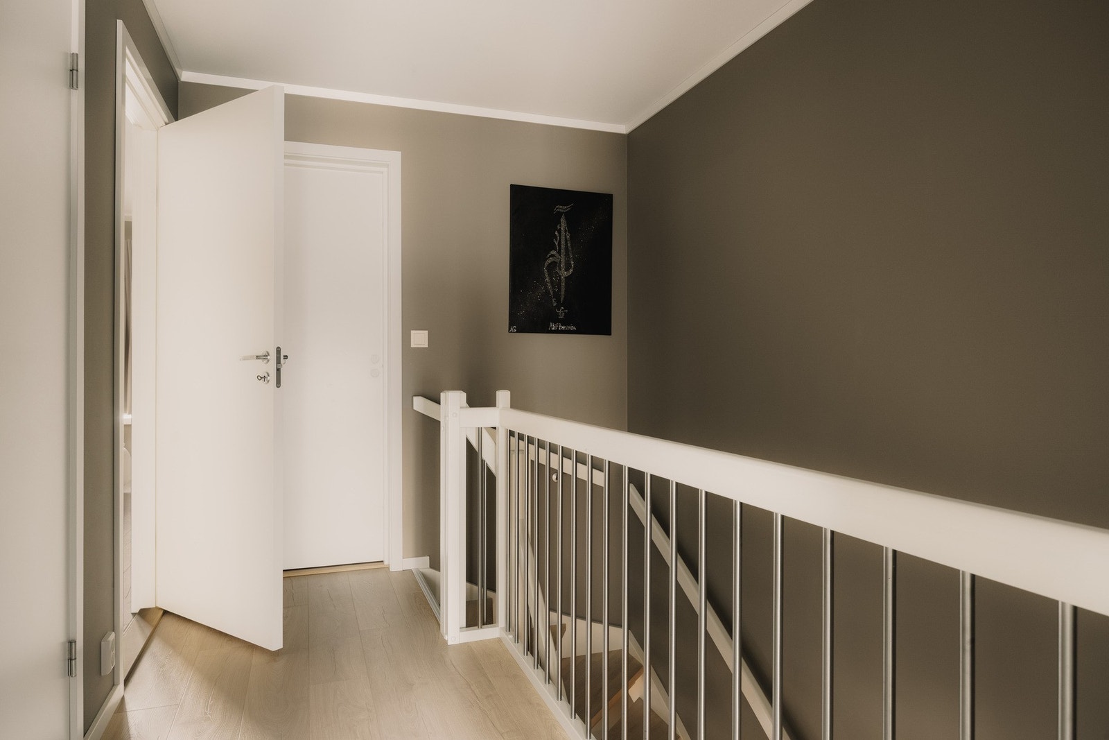Trappen leder opp til boligens andre etasje, hvor et lyst gangareal binder soverommene og badet naturlig sammen. Galleribilde