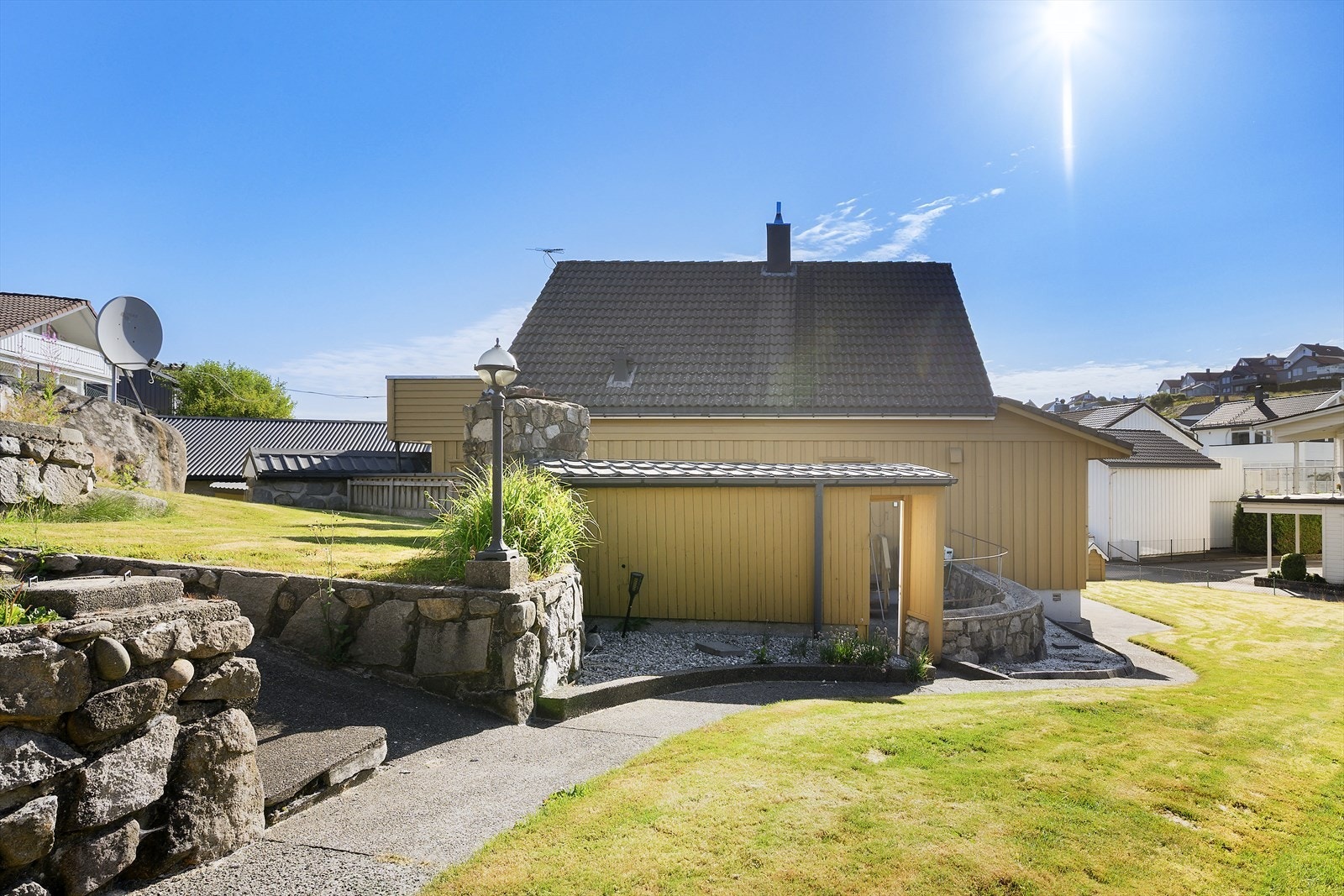 Lettstelt tomt som er pent opparbeidet med plen og steinmurer. Galleribilde