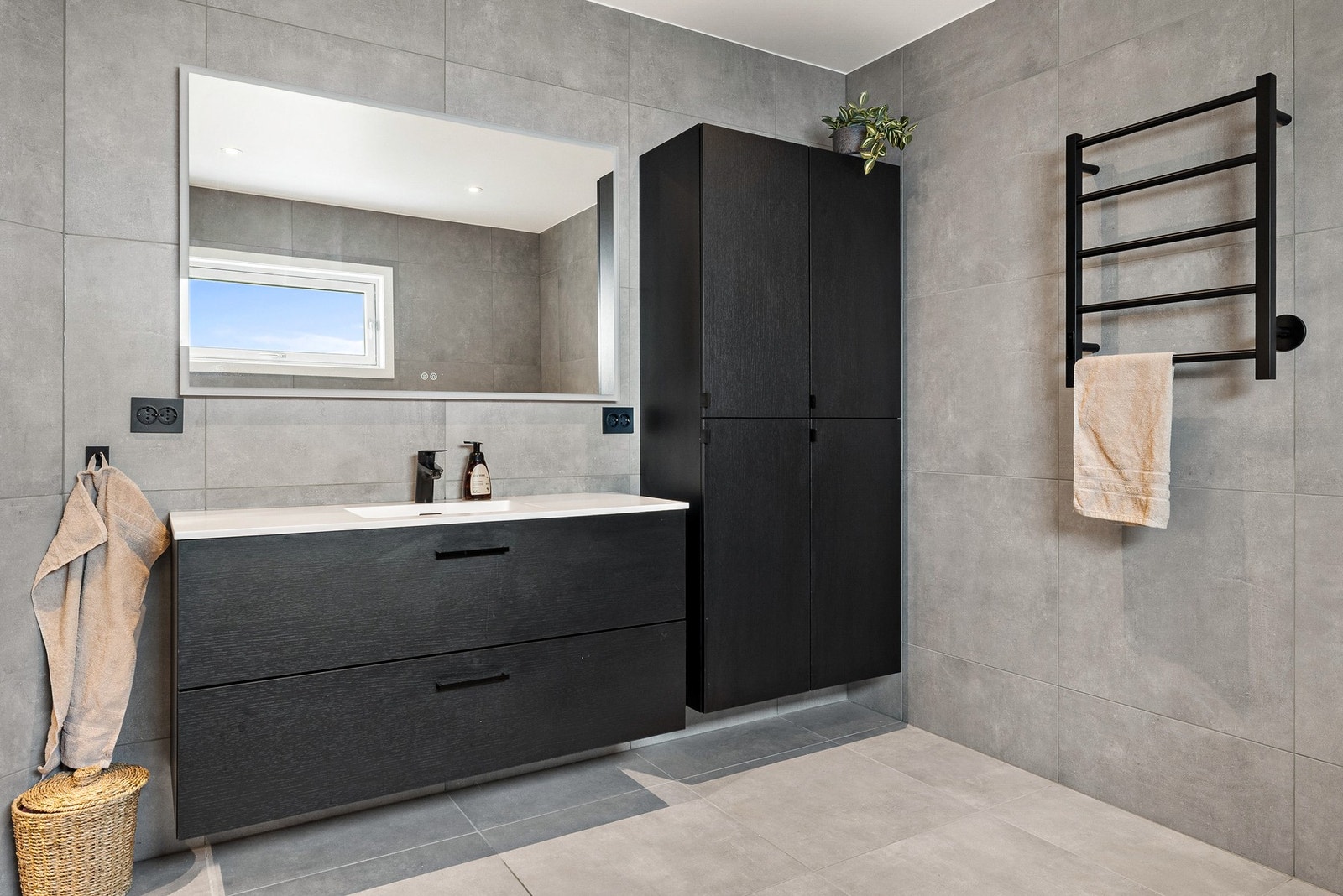 Badet er innredet med heldekkende servant, veggmontert toalett, badekar og dusjvegger/hjørne. Galleribilde