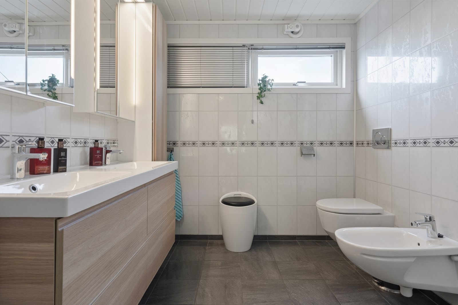 Hovedbad med dobbel servant i moderne baderomsinnredning og vegghengt toalett. Galleribilde