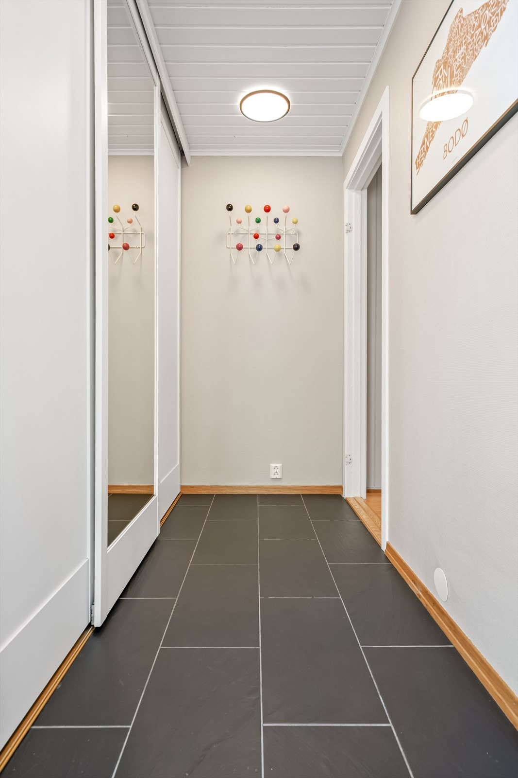 Entré med flislagt gulv og en praktisk skyvedørsgarderobe med speilfronter. Galleribilde