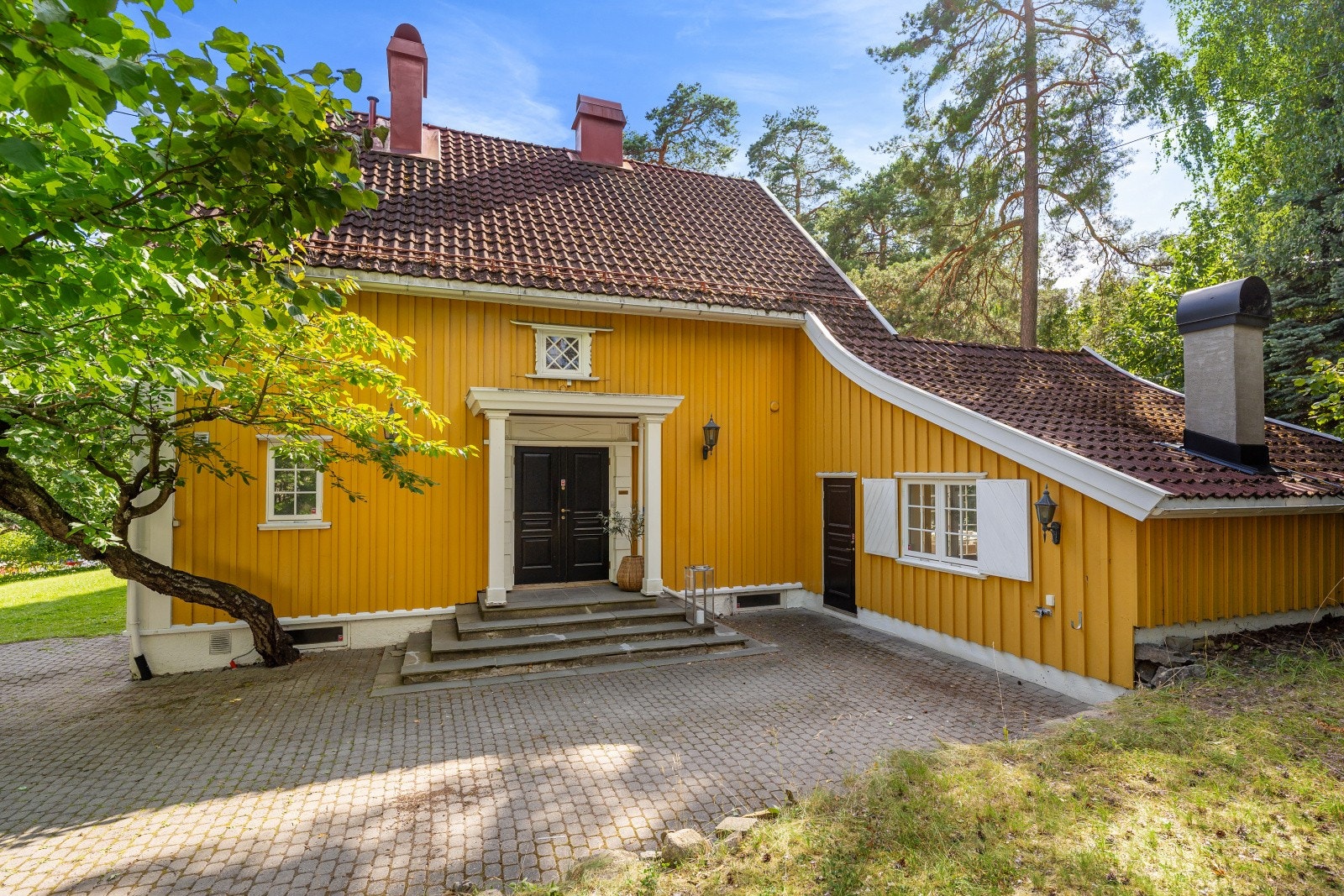 Overbygget inngangsparti med klassiske søyler og støpt trapp med skiferbelagte trinn som ønsker velkommen til boligen. Galleribilde
