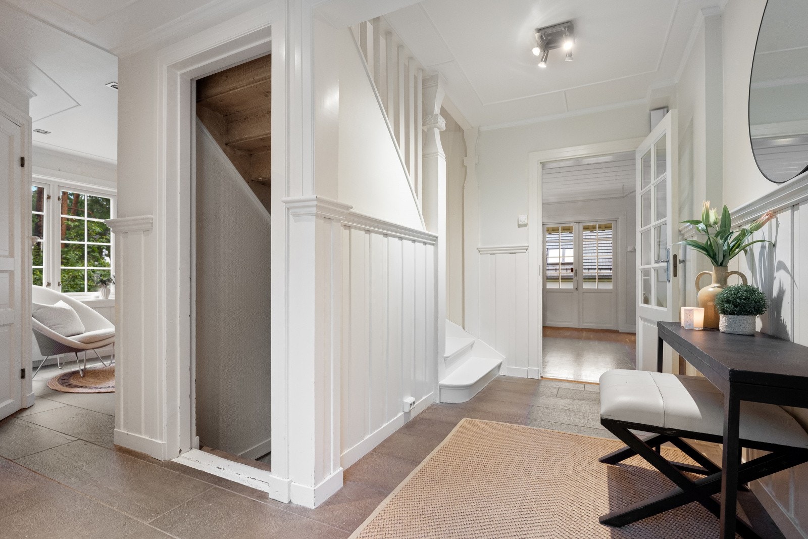 Romslig hall med skifer på gulvet og brystningspanel på veggene. Galleribilde