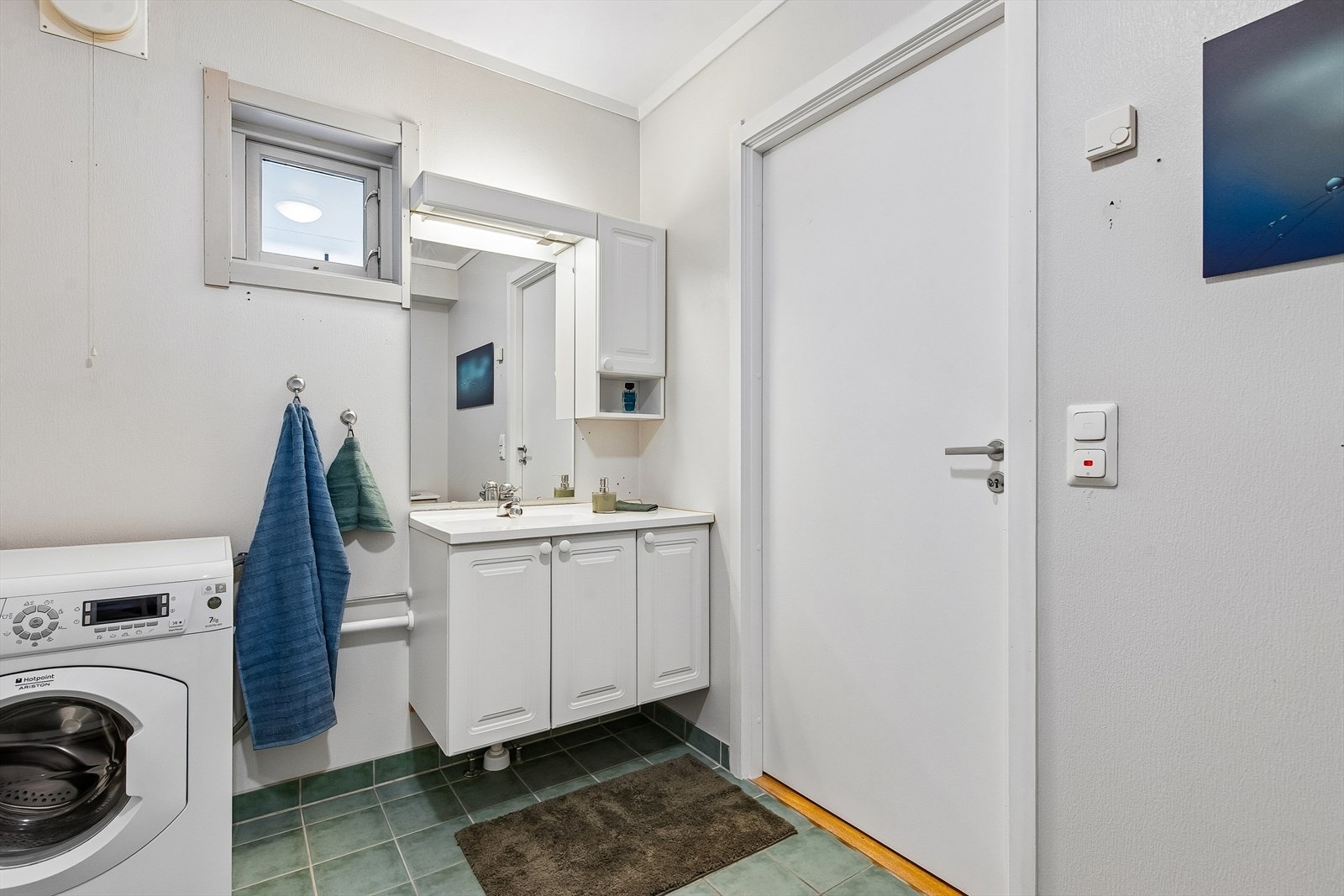 Badet har praktisk innredning med servant, speil, belysning og opplegg for vaskemaskin. Galleribilde