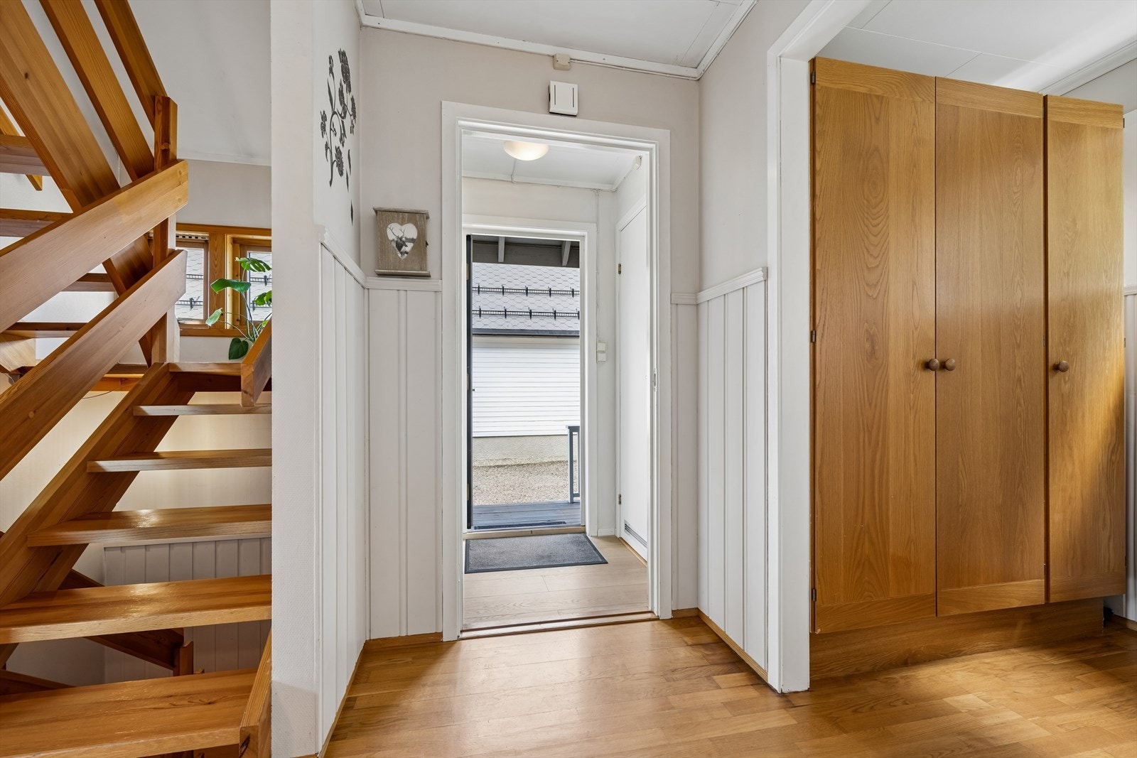 Lys entré med egen garderobe og lakkert tretrapp som forbinder etasjene. Galleribilde