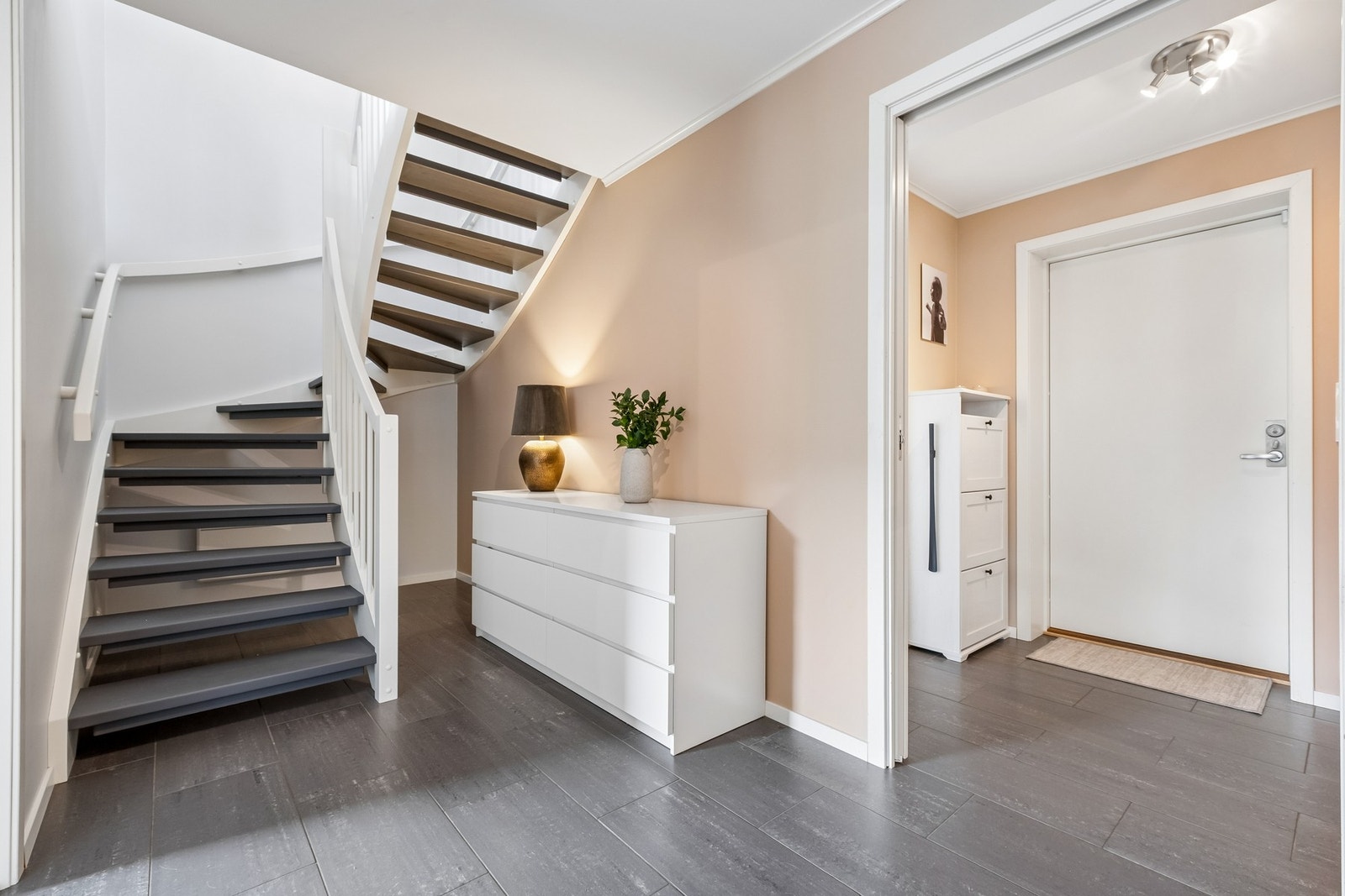 Trappen har et moderne design med åpne trinn og hvitt rekkverk. Galleribilde