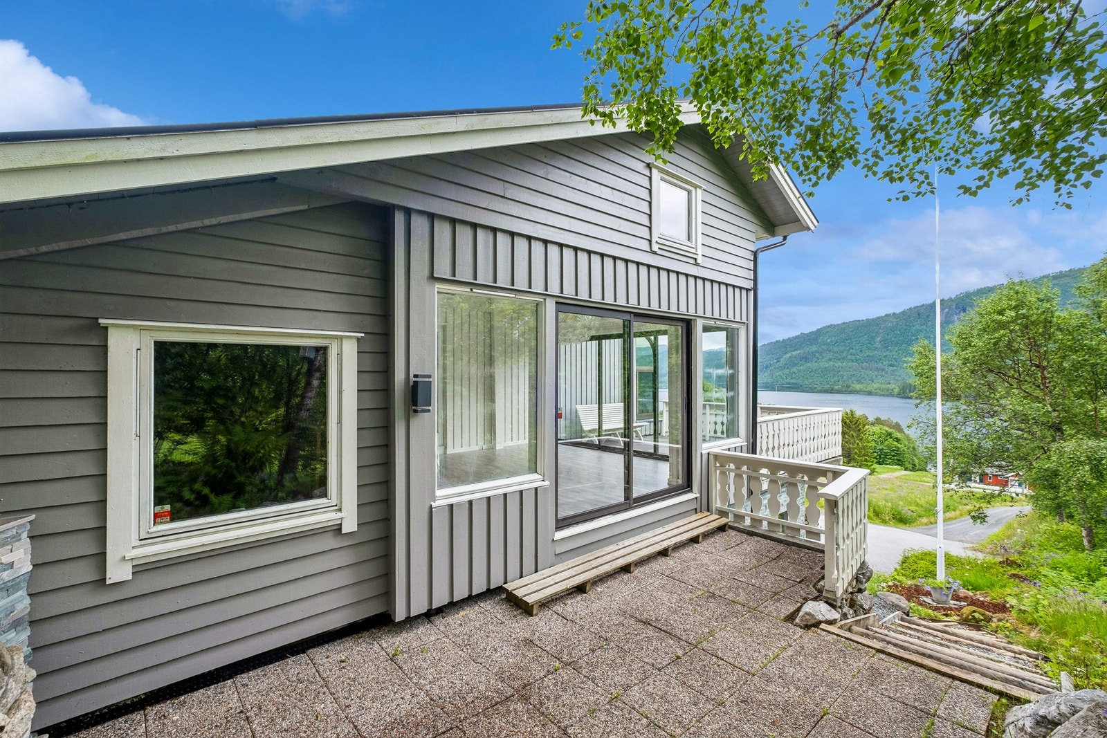 Fasade mot vest, glassdører til hagestue og terrasse. Trapp til gårdsplass og opp til terrasseområdet bak huset. Galleribilde