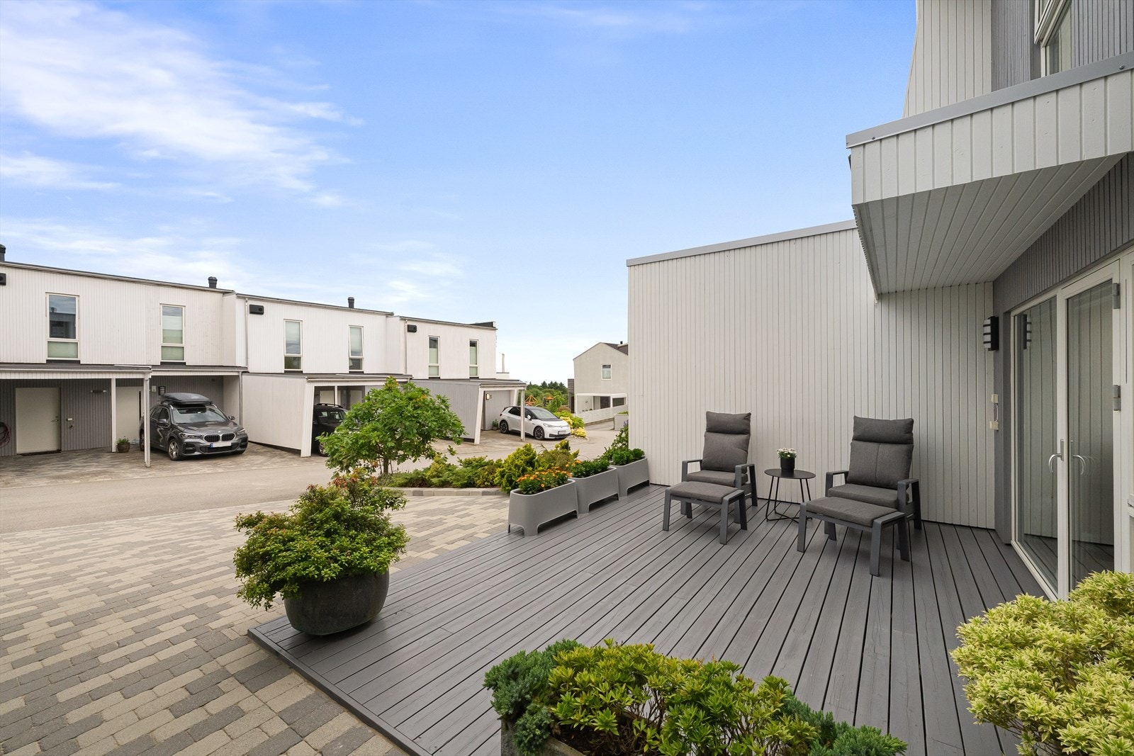 Gårdsplass med belegningsstein og parkering i egen carport. Galleribilde