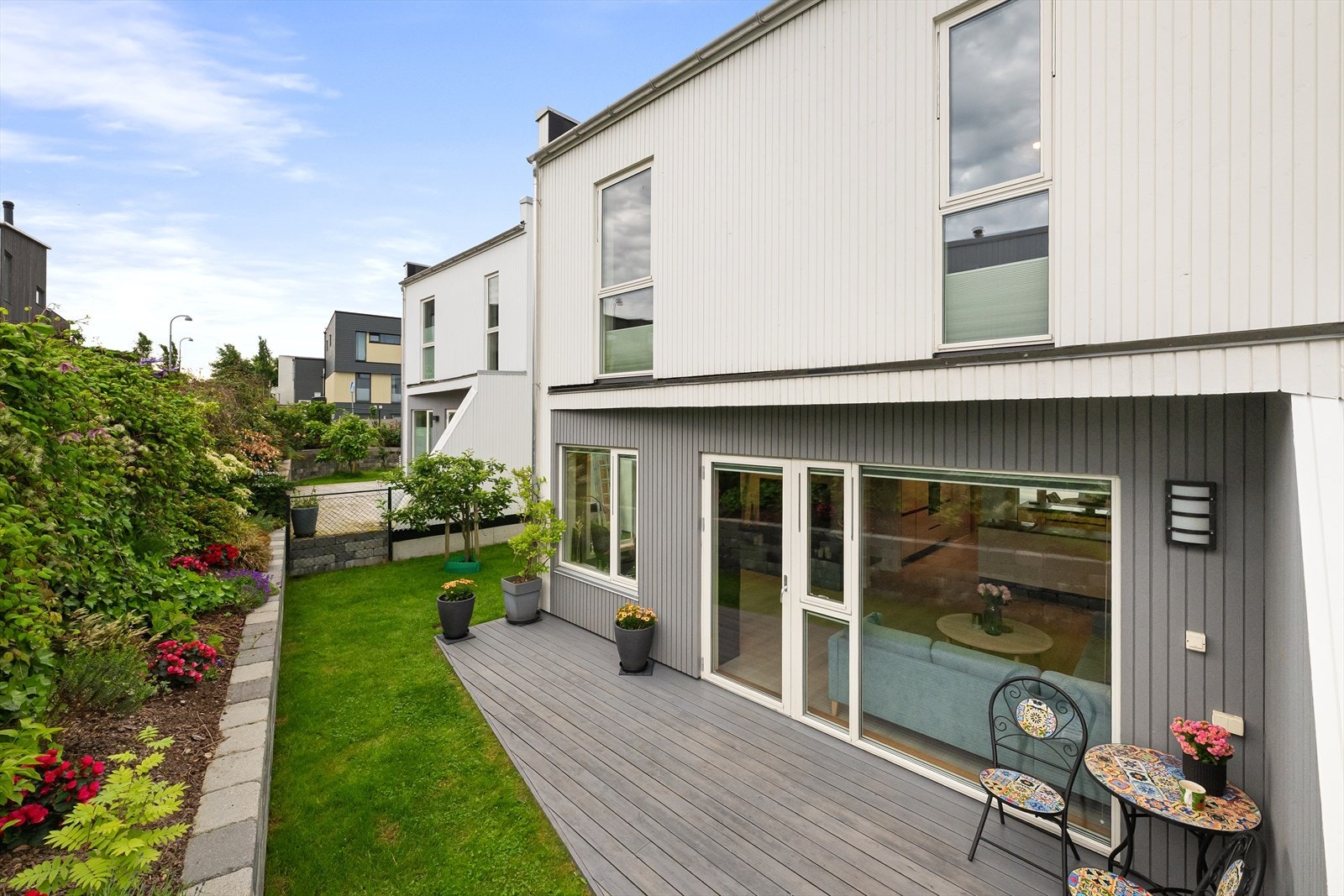 Hagen er pent opparbeidet med plen, beplantning og terrasseplatting. Galleribilde