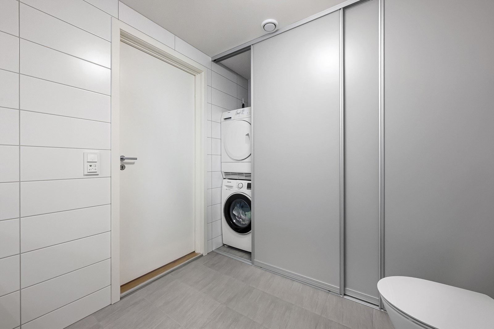 Badet har en smart løsning med opplegg for vaskemaskin og tørketrommel bak skyvedører. Galleribilde