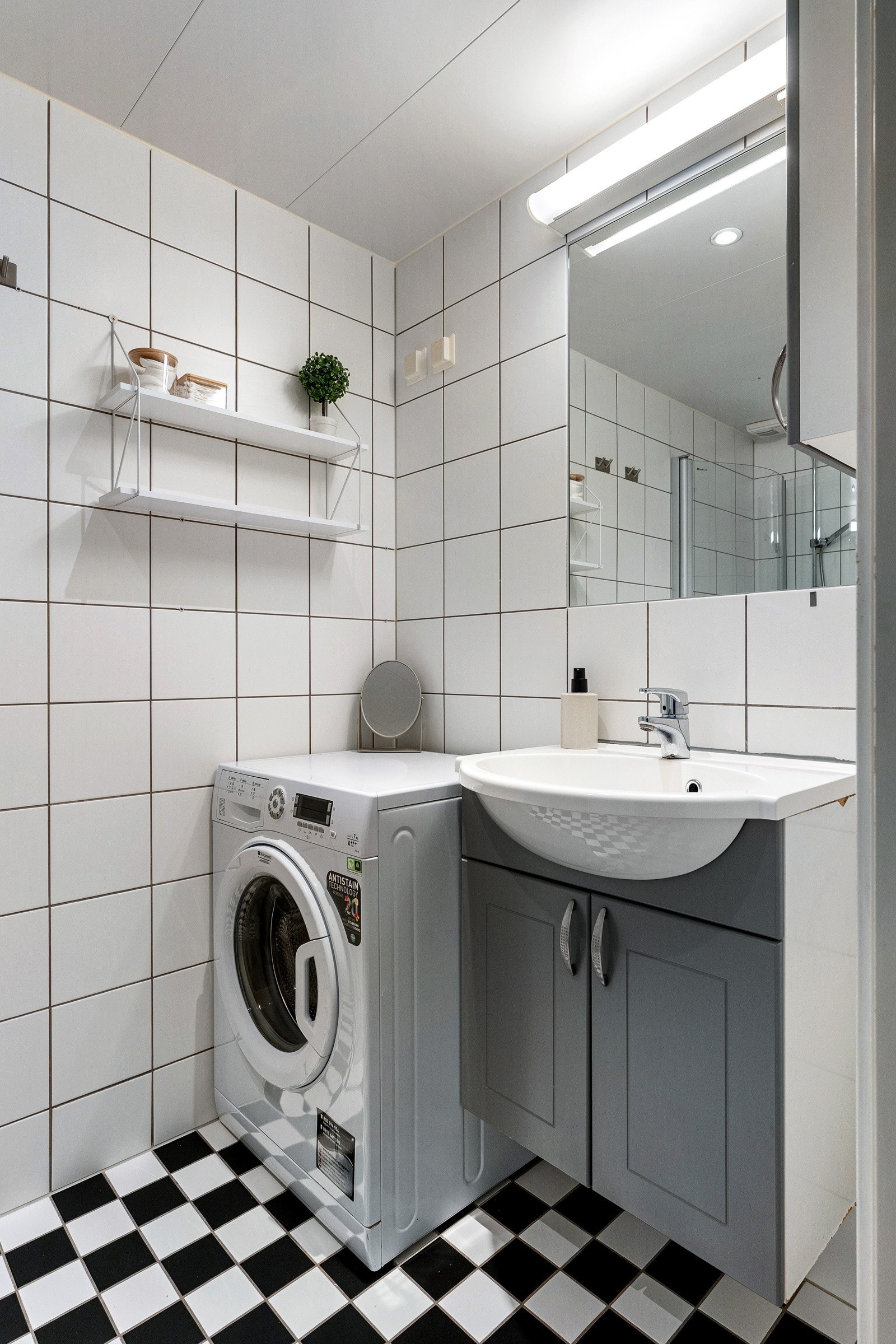 Flislagt bad/wc/vaskerom med gulvvarme og downlights i himling. Moderne baderomsinnredning med heldekkende servant og speil