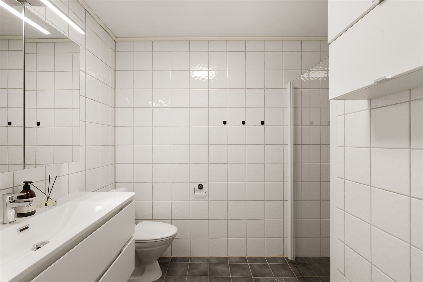 Lyst og tidløst bad med gulvvarme og flislagte overflater på gulv og vegger. Galleribilde