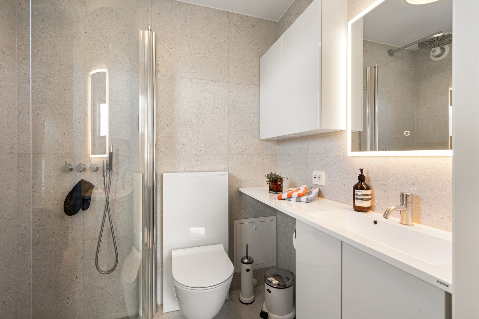 Badet i hovedetasjen ble fornyet i 2024 og er utført av OK Bad. Her er det valgt en rolig og tidløs materialpalett med store fliser i varme gråbeige toner på gulv og vegger. Galleribilde