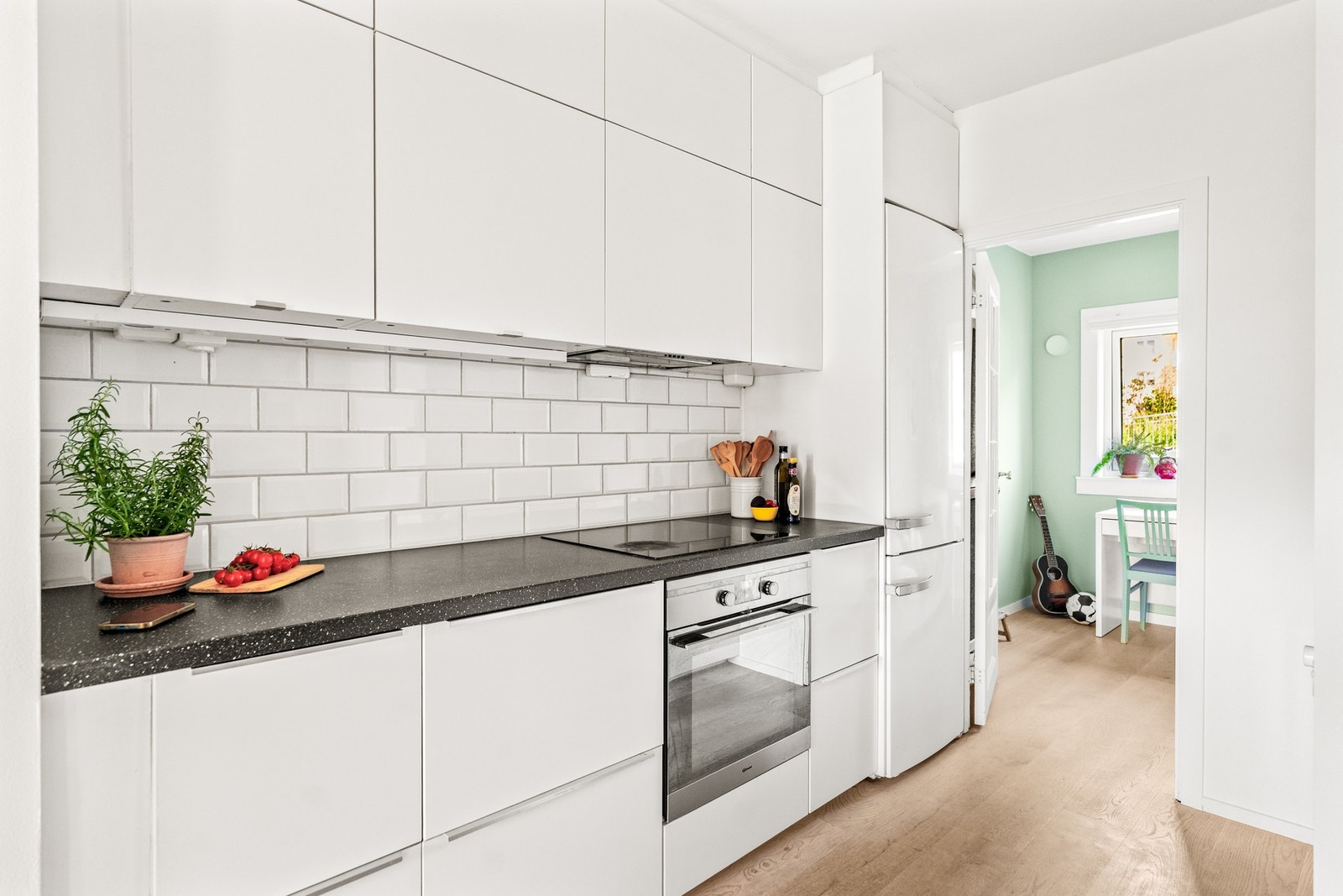 Kjøkken med en stilren innredning fra IKEA med glatte fronter og benkeplate i laminat med toppmontert metallvask og ettgreps kjøkkenarmatur. Galleribilde