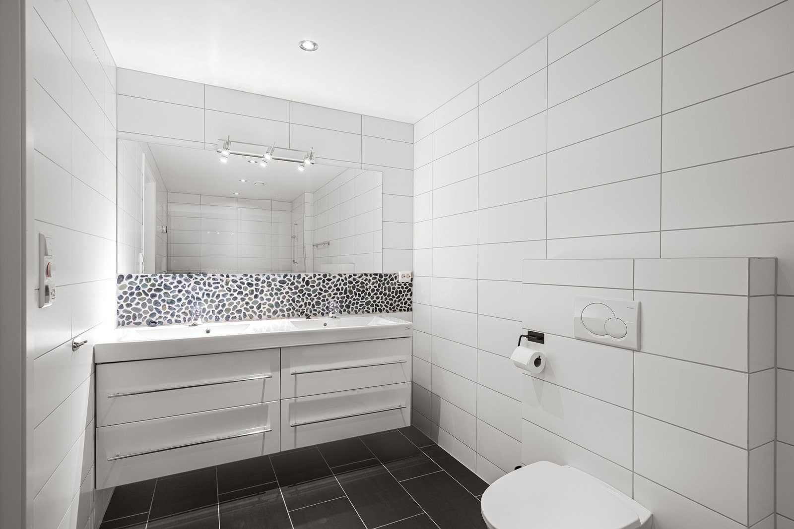 Badet har flislagte vegger og gulv, med rullestein i dusjnisjen som gir et eksklusivt uttrykk. Rommet har elektriske varmekabler i gulv som gir god komfort. Galleribilde