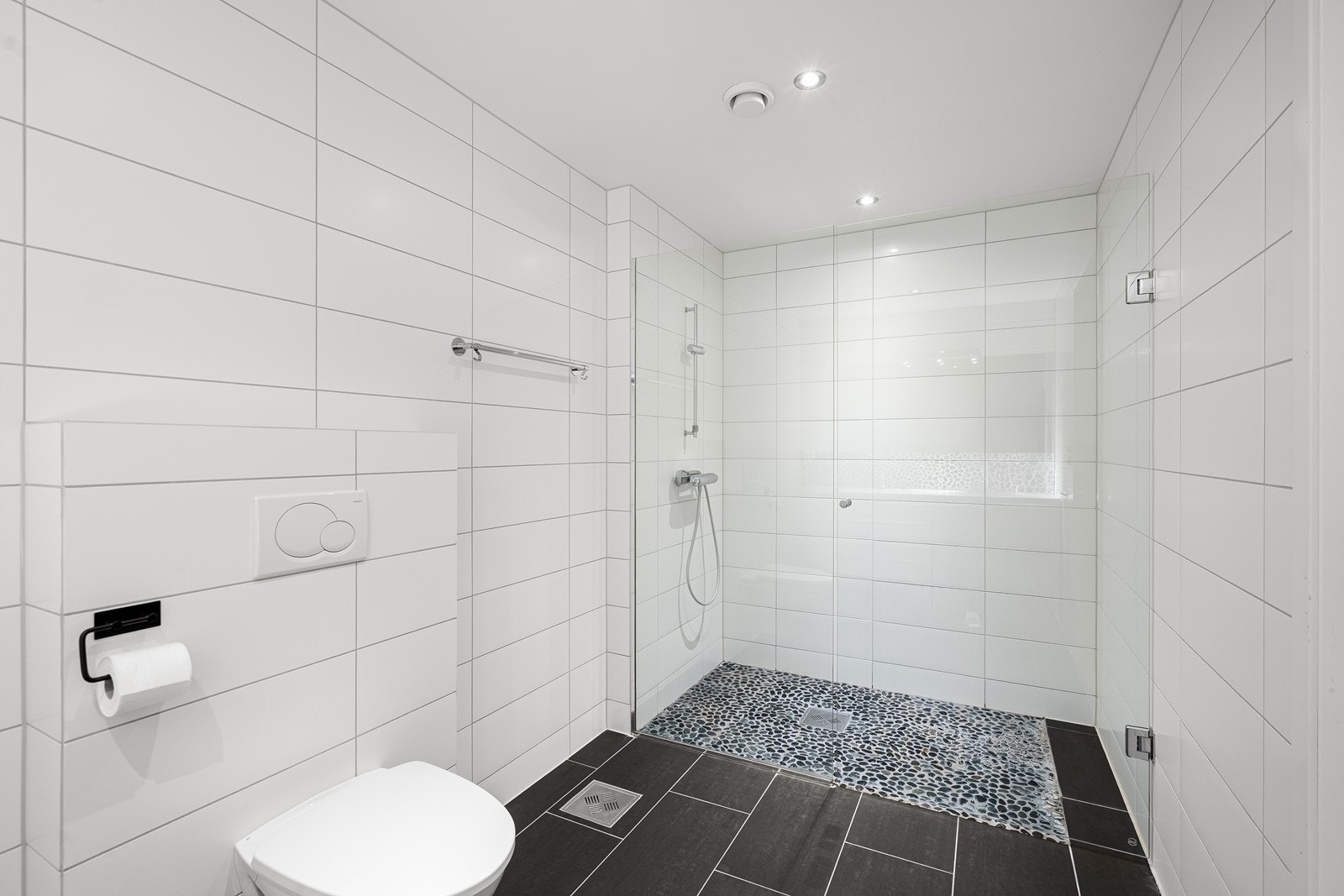 Badet er innredet med dobbel servant i skuffeseksjon, vegghengt toalett og dusj med glassdører. Galleribilde