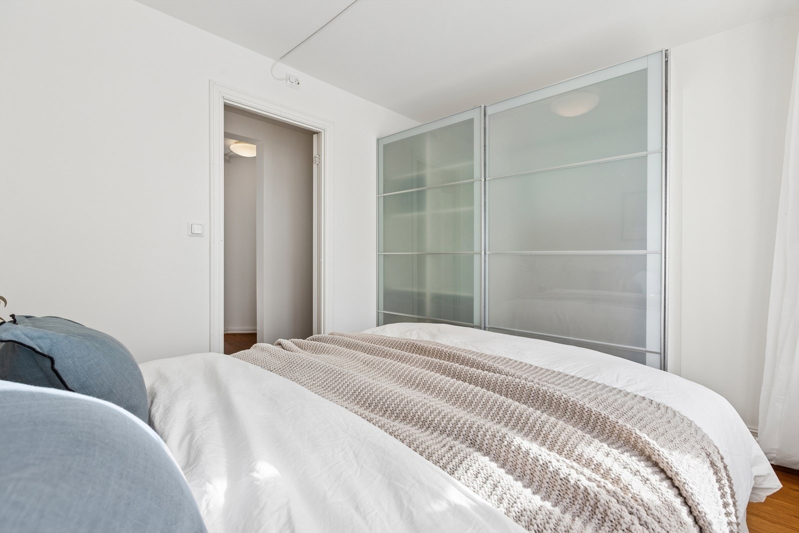 Et garderobeskap med skyvedører i frostet glass gir gode oppbevaringsmuligheter samtidig som gulvplassen utnyttes effektivt. Galleribilde