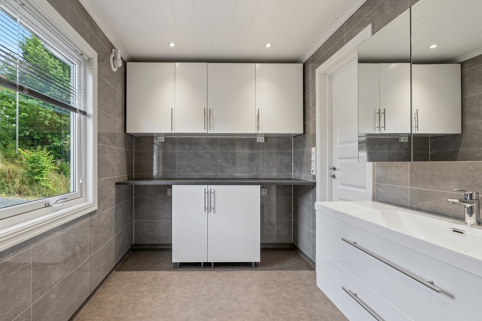 Praktisk vaskeromsdel på badet med benkeplate og opplegg for vaskemaskin. Galleribilde