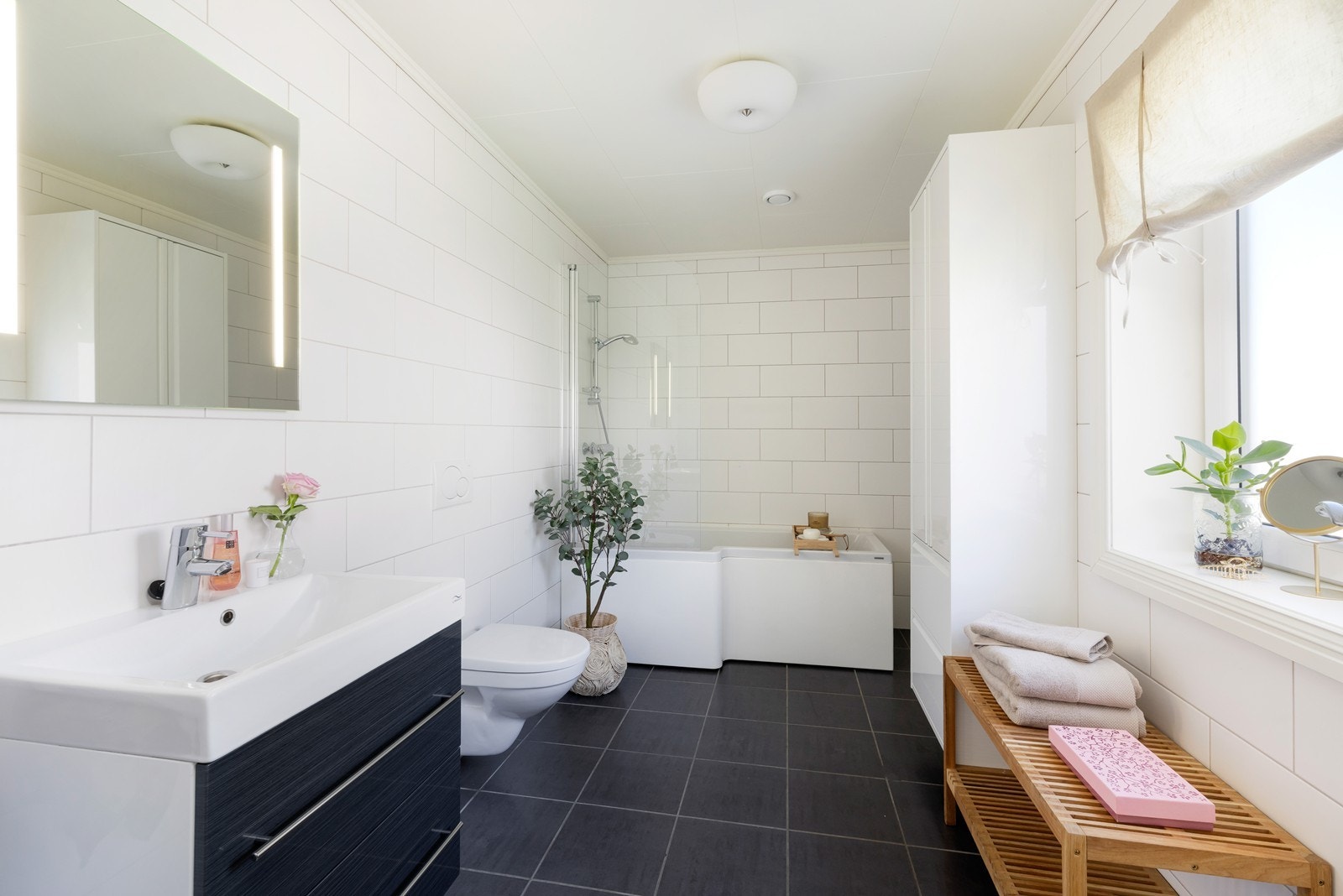 Badet er innredet med badekar/dusj, servant innredning, skap og toalett. Galleribilde