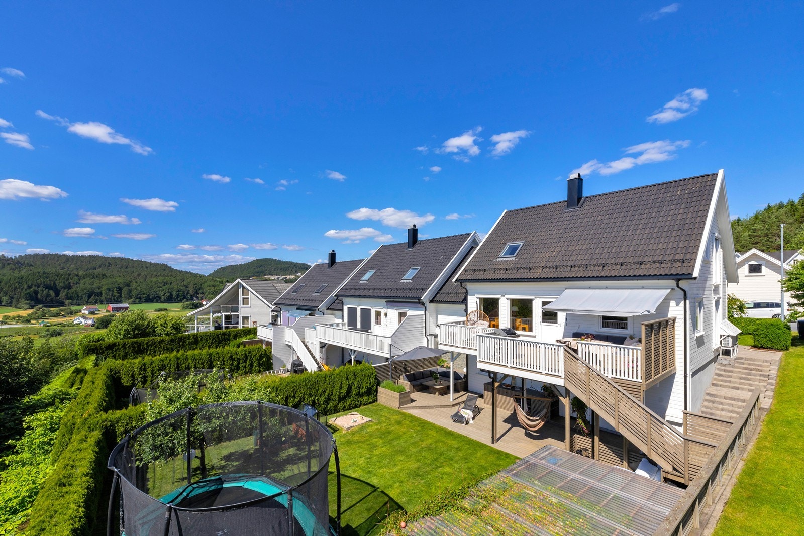 Veranda med trapp videre ned til en delvis overbygd markterrasse. Galleribilde