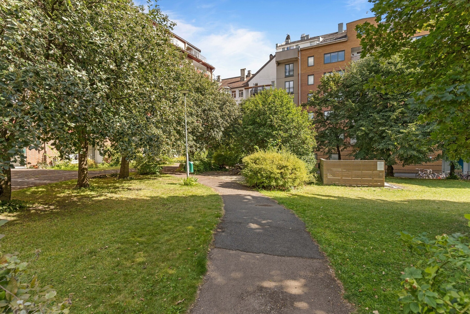 Flott, opparbeidet bakgård med beplantning, hagemøbler, sykkelparkering og vognparkering. Galleribilde