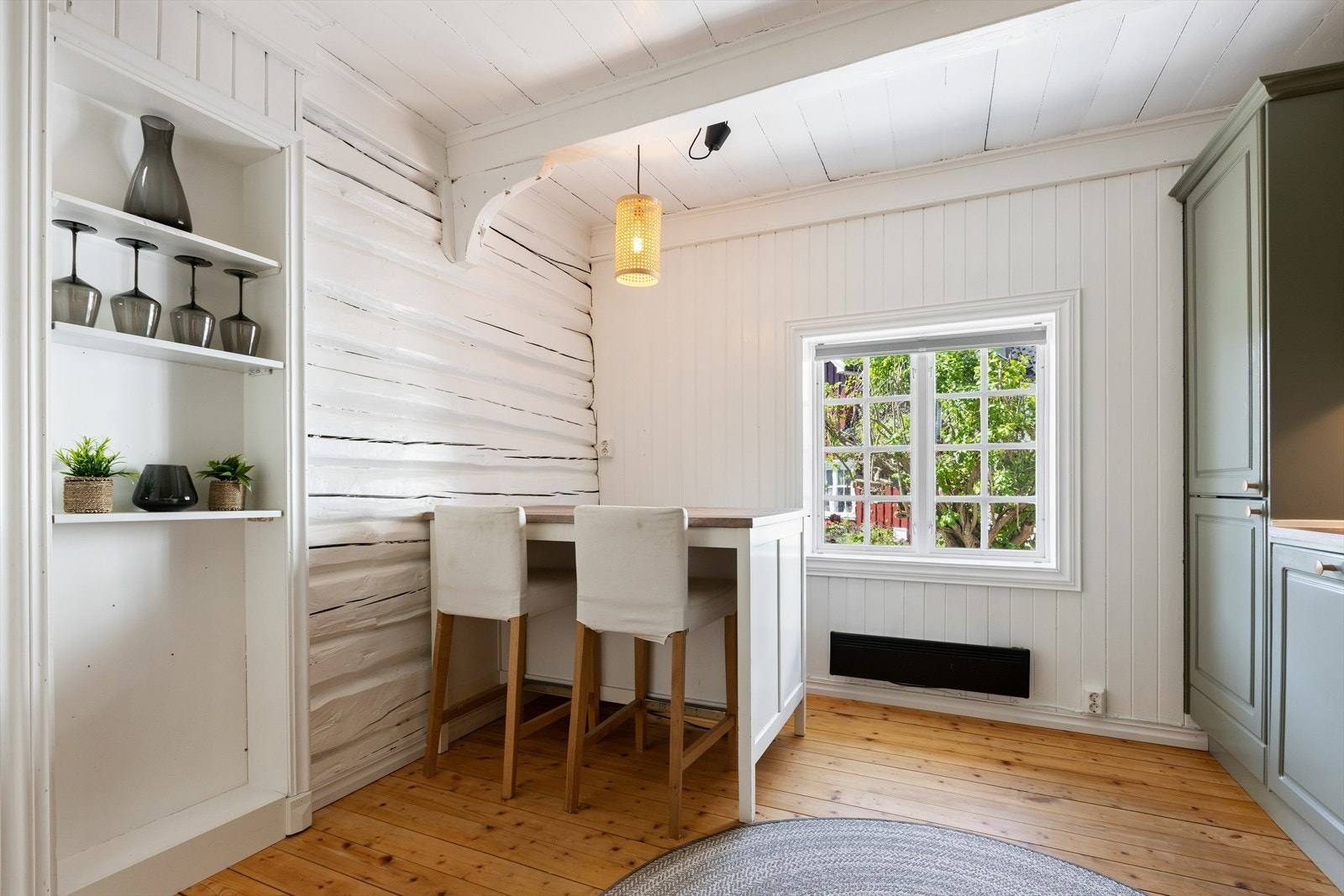 Lyse overflater, tregulv og fine detaljer skaper en lun og innbydende atmosfære, mens spiseplassen ved vinduet gir en hyggelig ramme for hverdagens måltider. Galleribilde