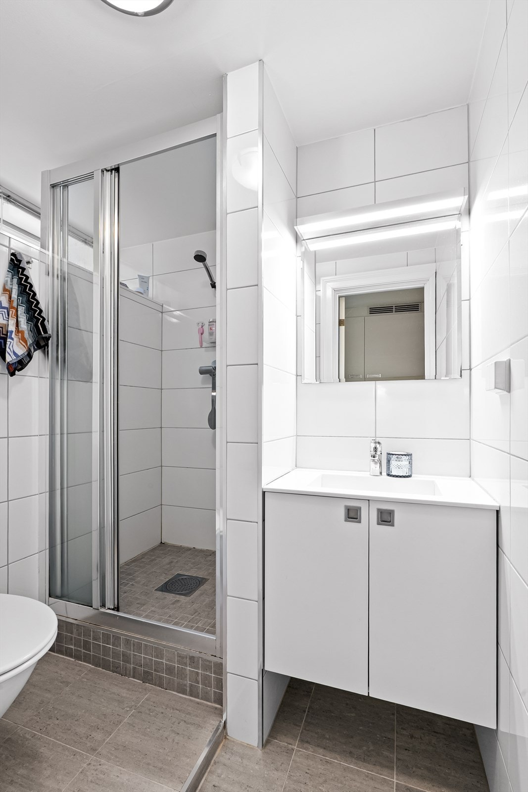 Flislagt baderom fra 2016. Badet er innredet med en nedfelt servant, overhengende speil og belysning. Det er montert elektriske varmekabler i gulv Galleribilde