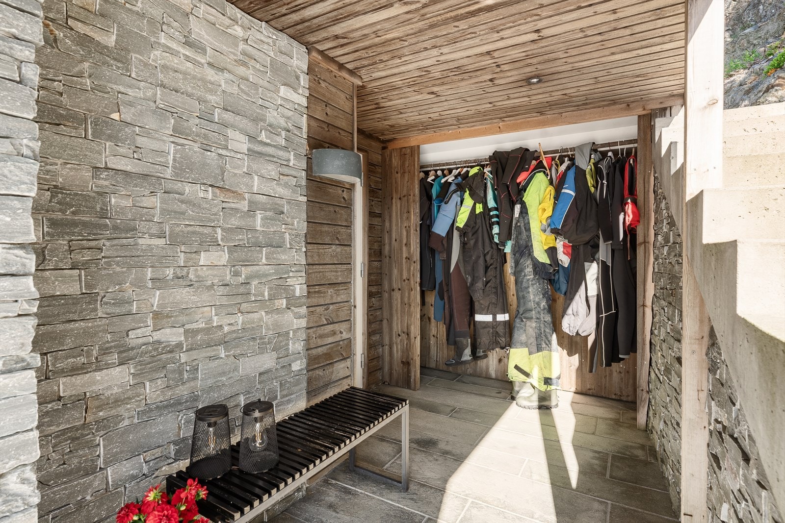 I forbindelse med inngangspartiet til hytta er det en overbygget bod hvor det er plass til det mest nødvendige på hytta som våtdrakter, kjeledress og annet du vil henge opp. Legg merke til den flotte natursteinen som er lagt på deler av ytterveggene. Galleribilde
