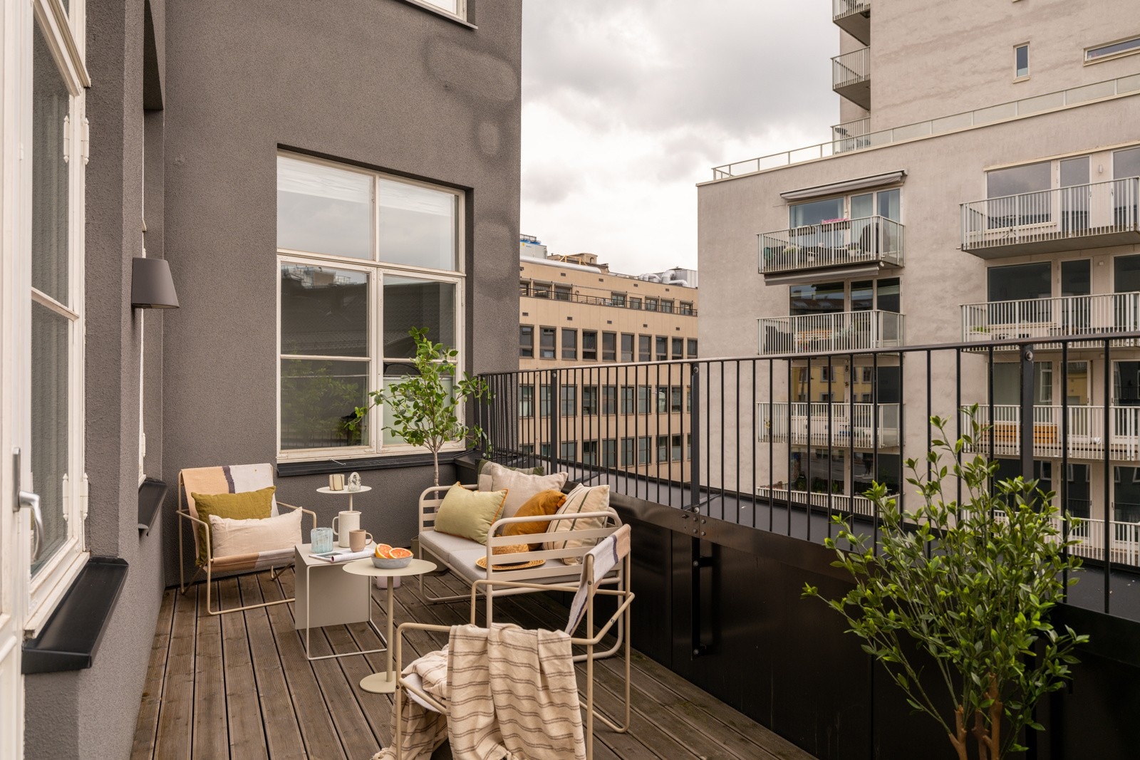 Balkongen har terrassebord på gulv, rekkverk av metall og utebelysning på vegg. Galleribilde