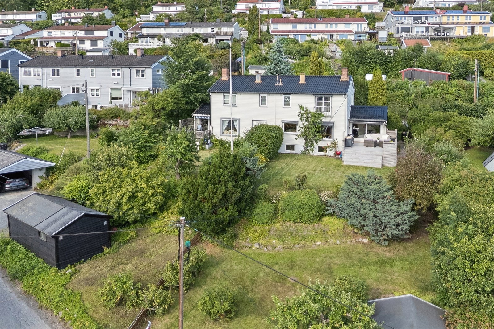 Hage over flere nivåer med planter som blomstrer gjennom hele sesongen - opp mot veggen finner du et ferskentre, hvor det er i år er godt med frukt - tyder på gode solforhold! Galleribilde