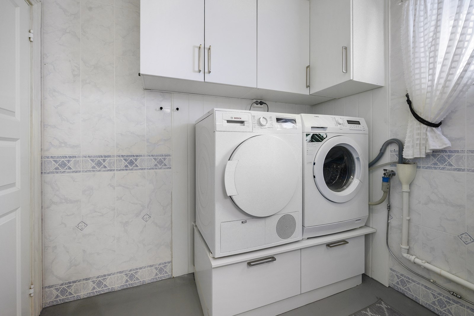 Badet er kombinert vaskerom med praktisk opplegg for vaskemaskin og tørketrommel. Galleribilde
