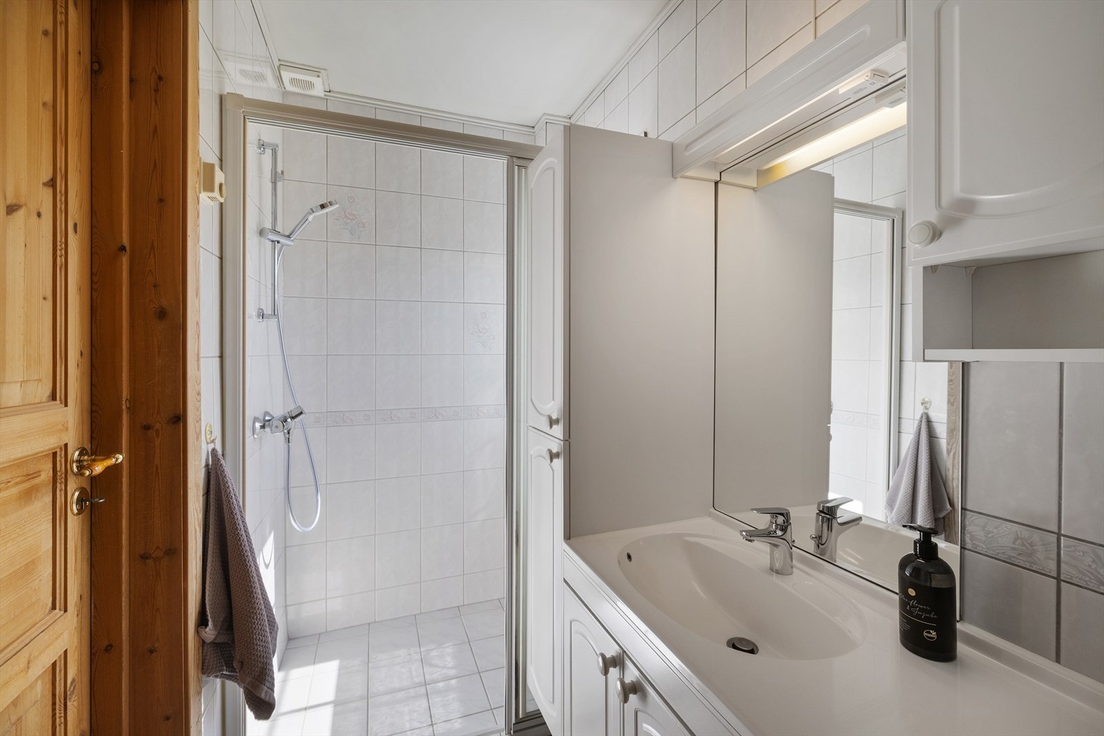 Badet er utstyrt med dusjhjørne, servant med innredning og mekanisk avtrekksvifte. Galleribilde