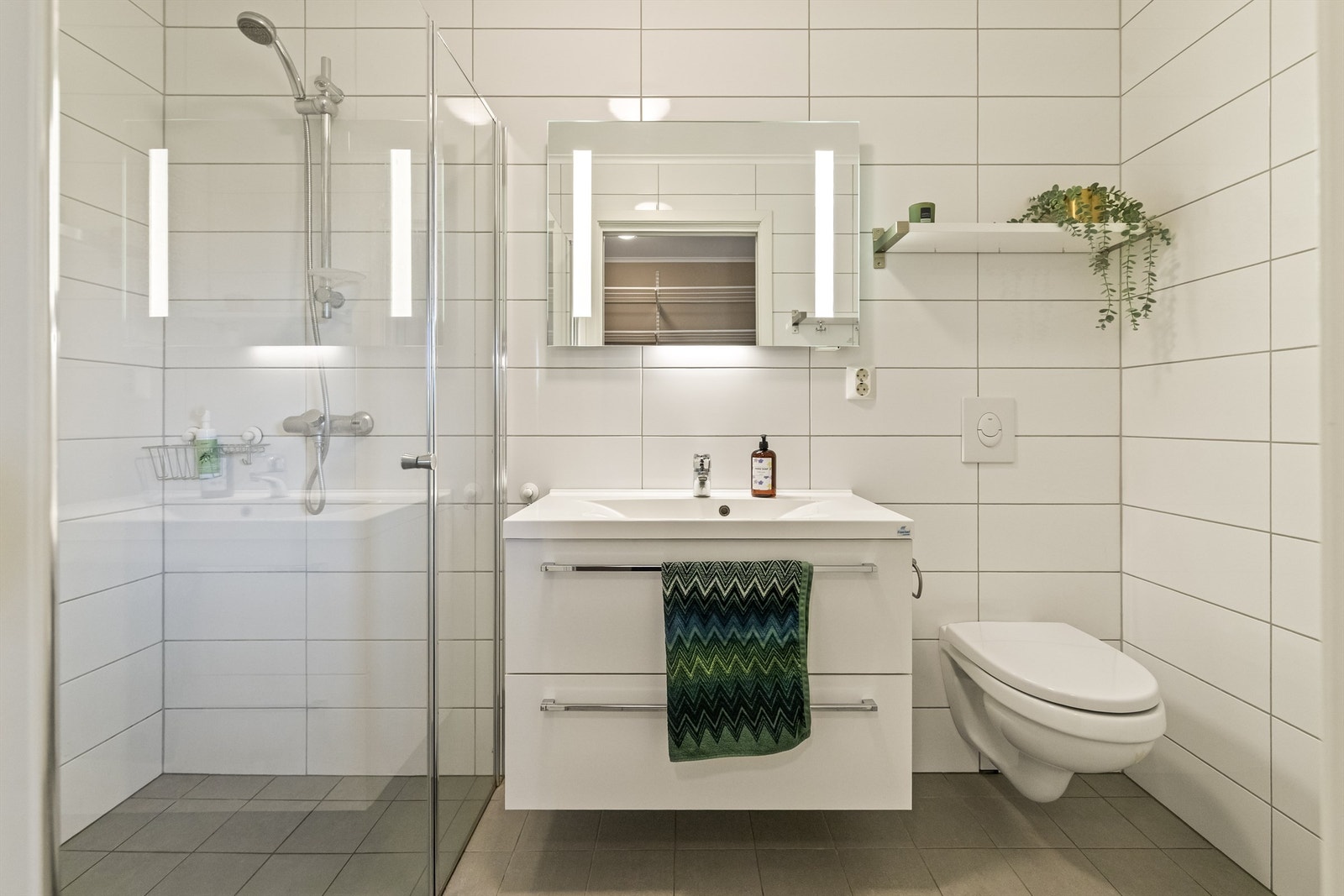 Bad fra byggeår med flislagte overflater på gulv og vegger. Gulvet har behagelig varme som gir ekstra komfort i hverdagen. Galleribilde