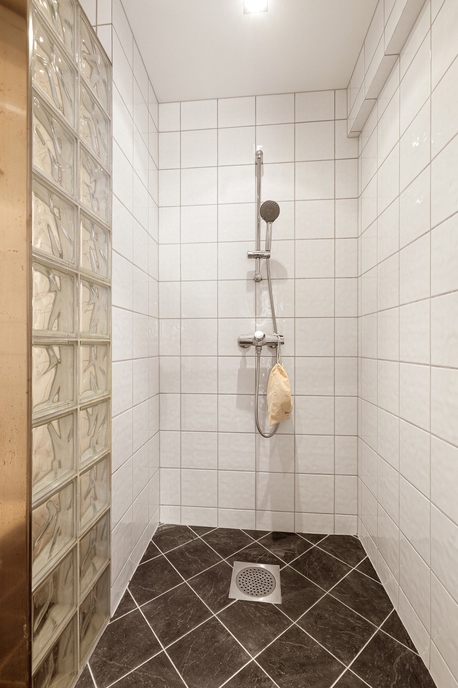 Videre er badet utstyrt med vegghengt toalett, dusjhjørne med glassvegg og opplegg for vaskemaskin. Galleribilde