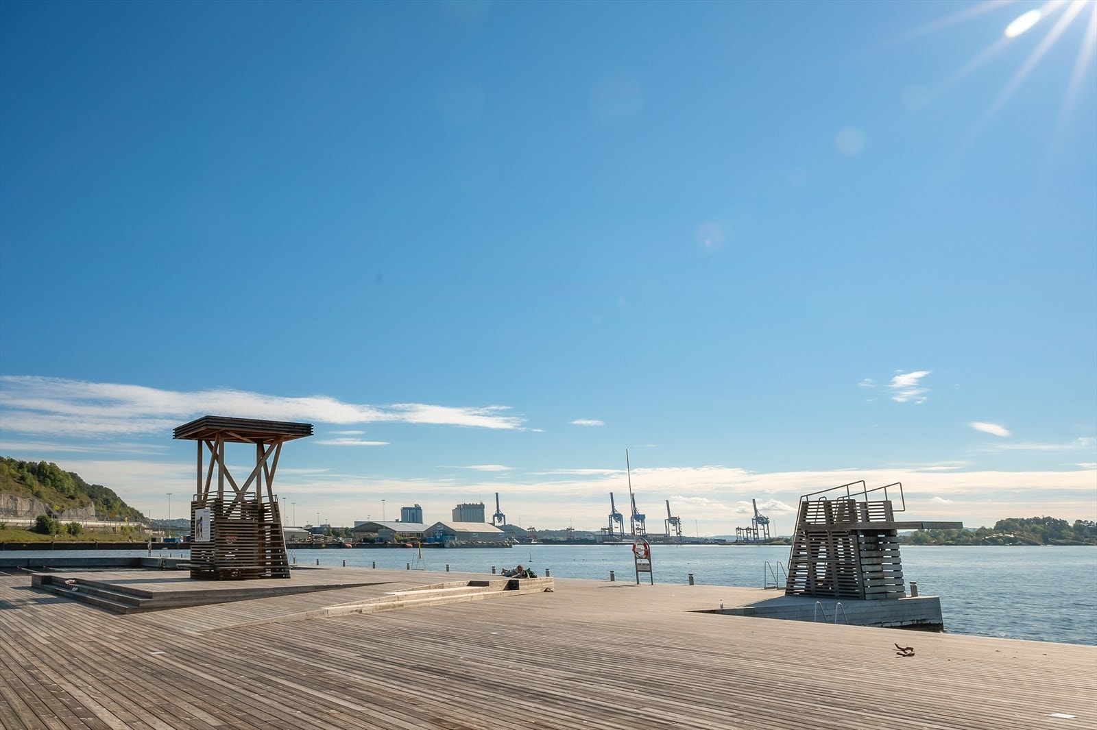 Her finnes barnevennlig sandstrand, gresskledd parkområde, rikelig med sitteplasser og stupetårn Galleribilde