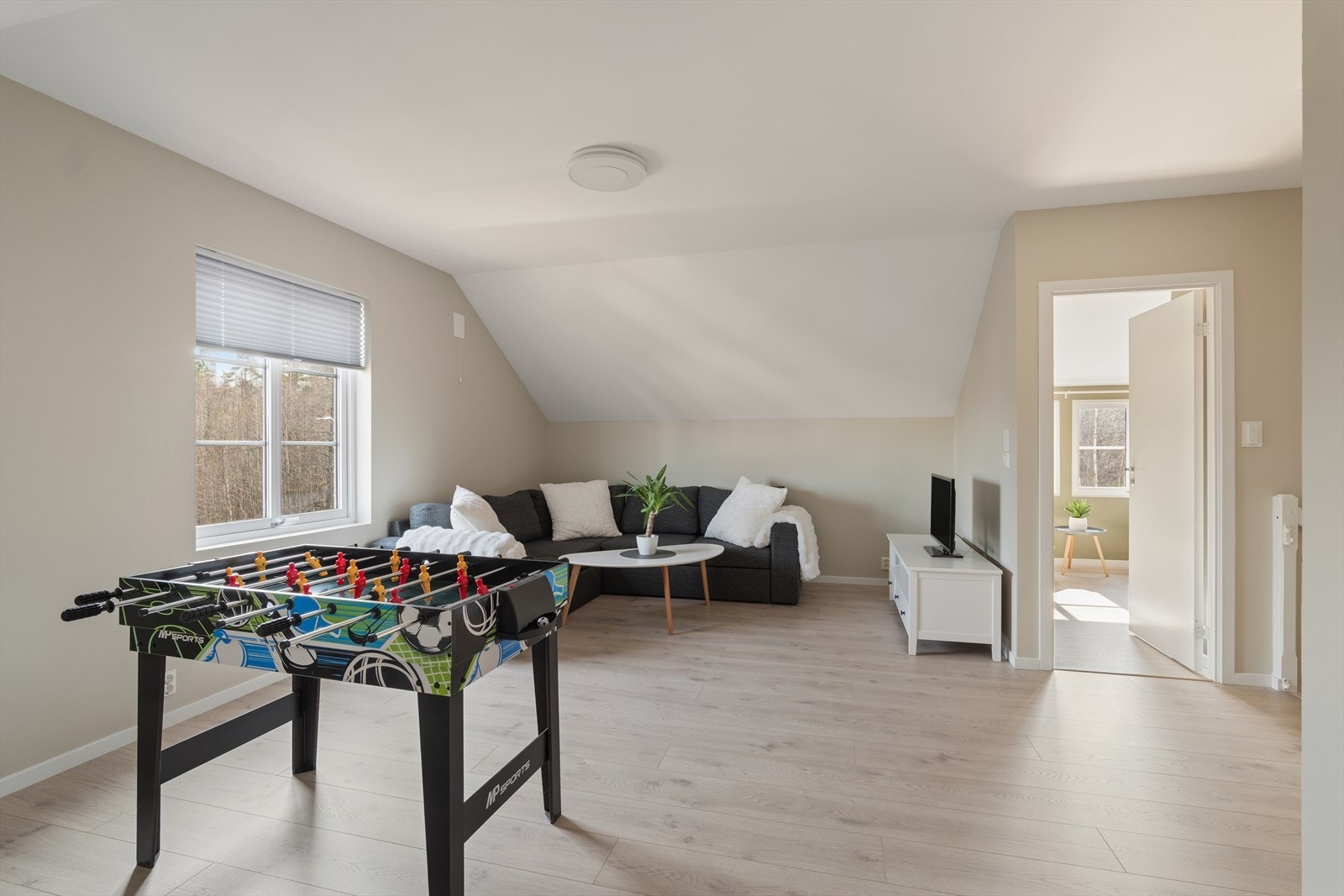 Loftstuen fremstår som et lyst og luftig oppholdsrom, perfekt som TV-stue, lekerom eller en rolig sone for avslapning. Galleribilde