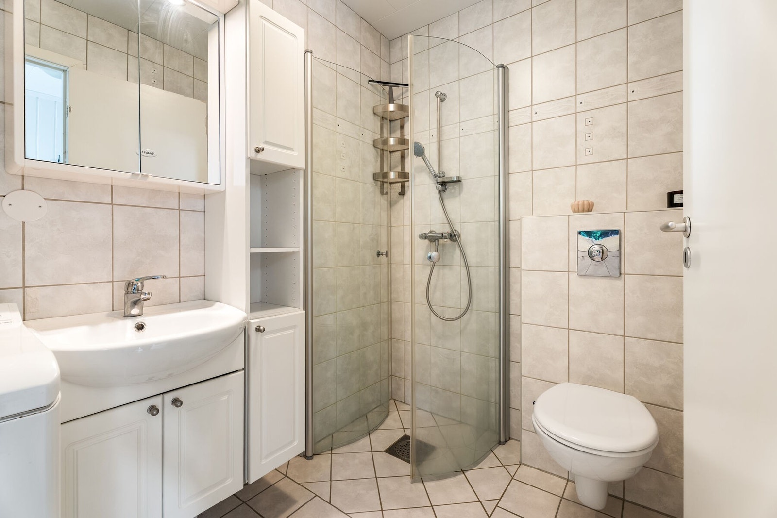 Badet er praktisk innredet med varmekabler i gulv, veggmontert toalett og servant med ettgreps blandebatteri. Galleribilde