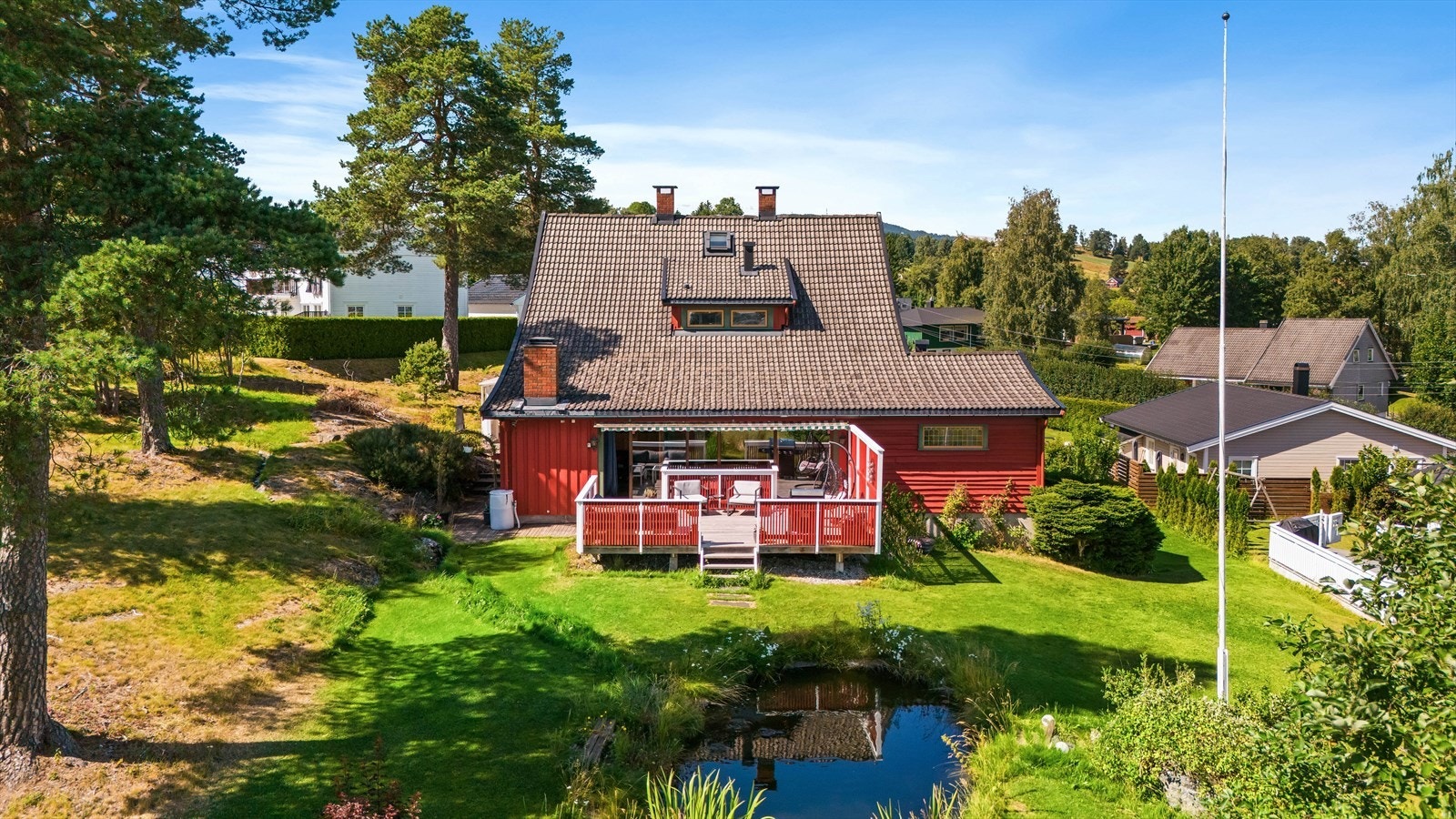 Den store tomten er opparbeidet med plen, beplantning og en egen hagedam. Galleribilde