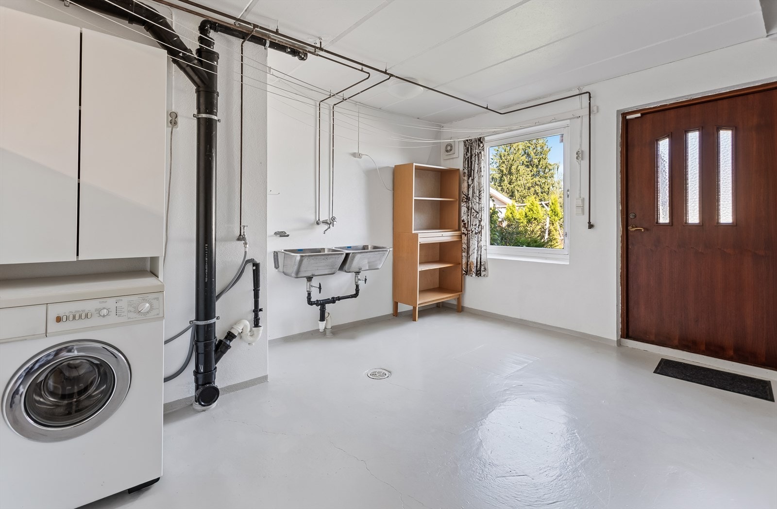 Praktisk rom i kjelleren med sluk i gulvet og opplegg for vaskemaskin og tørketrommel. Galleribilde