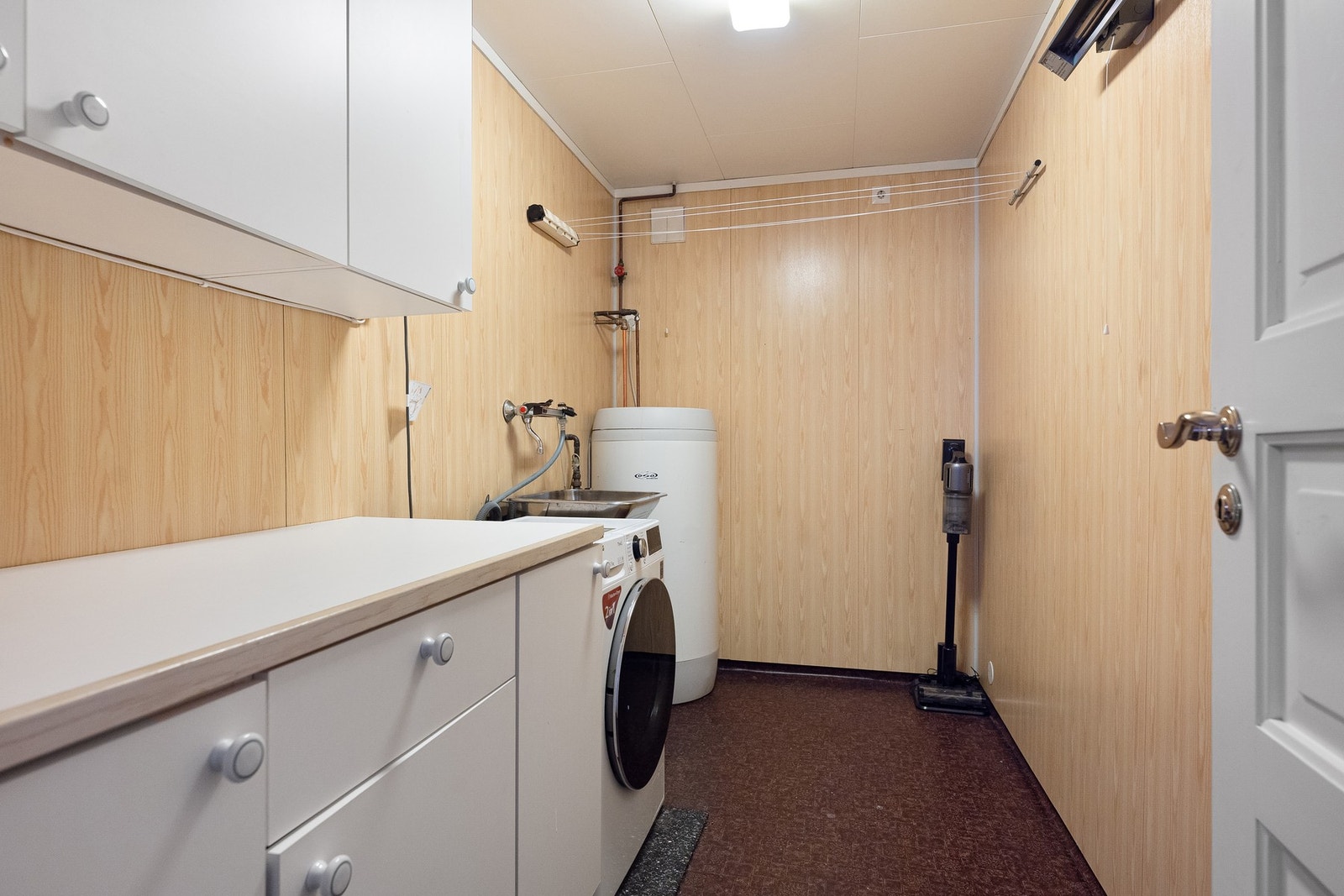 Praktisk vaskerom med utslagsvask, oppbevaringsplass og opplegg for vaskemaskin. Galleribilde