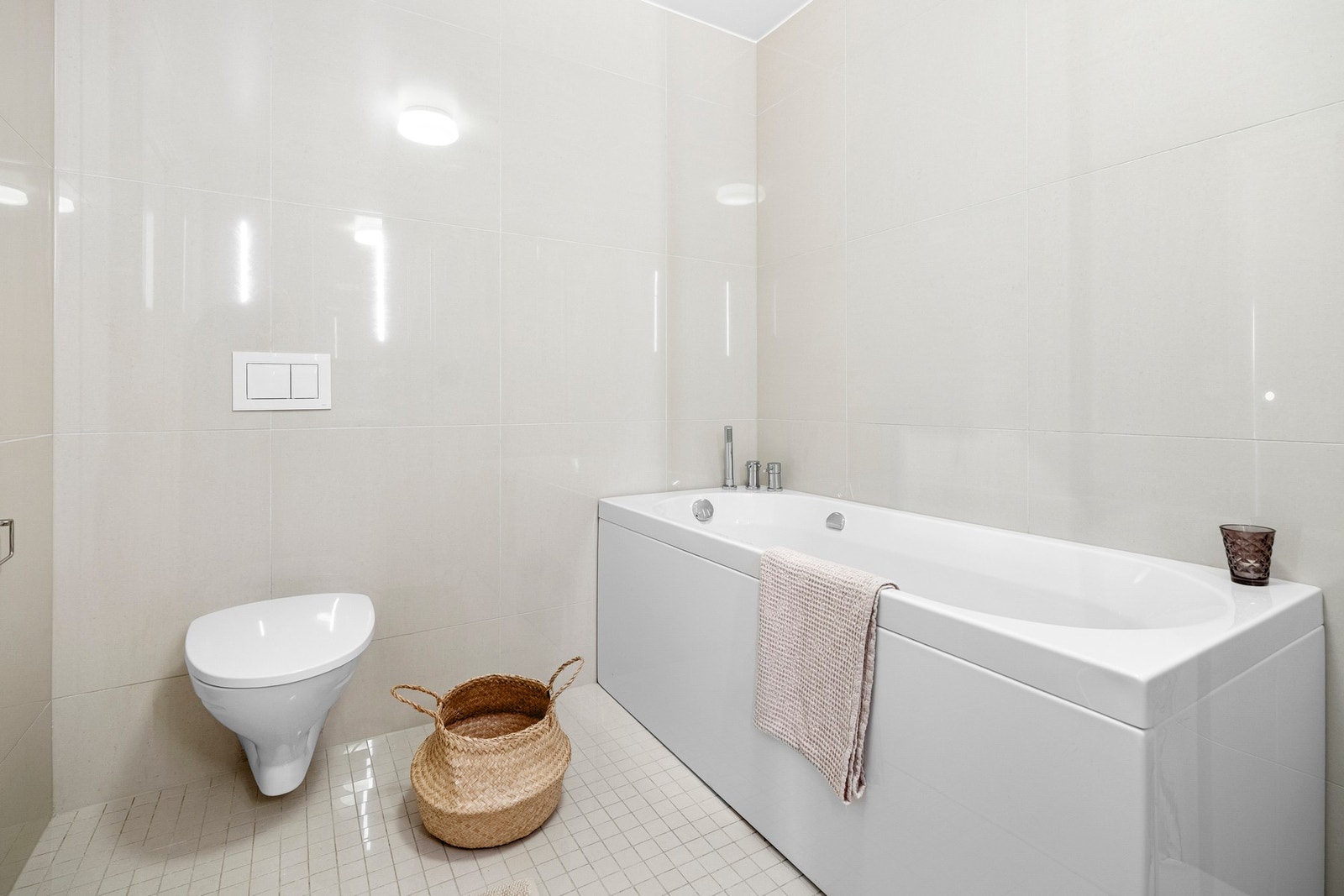 Badet har et lyst og tidløst uttrykk med flislagte vegger og gulv, behagelige varmekabler og en moderne, vegghengt innredning. Galleribilde